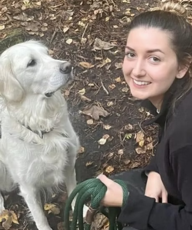 A female with brown hair kneeling next to a dog
