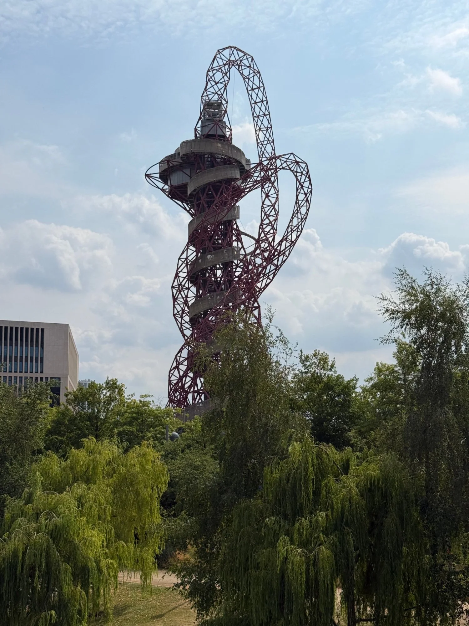 The red steel lattice tower of the ArcelorMittal Orbit observation structure standing tall against a bright sky in the Queen Elizabeth Olympic Park in London.