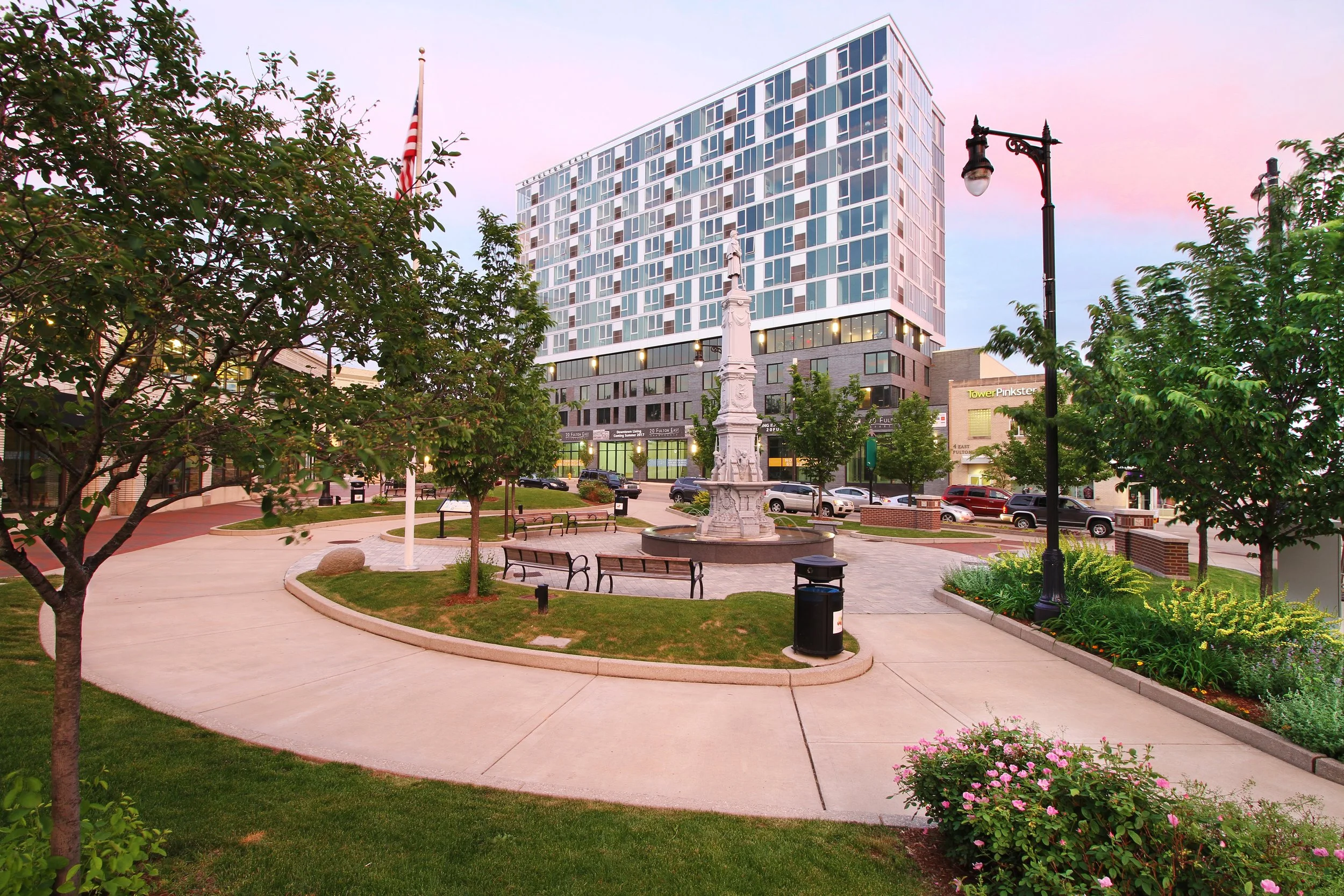 Urban park with memorial monument, pavers, and benches