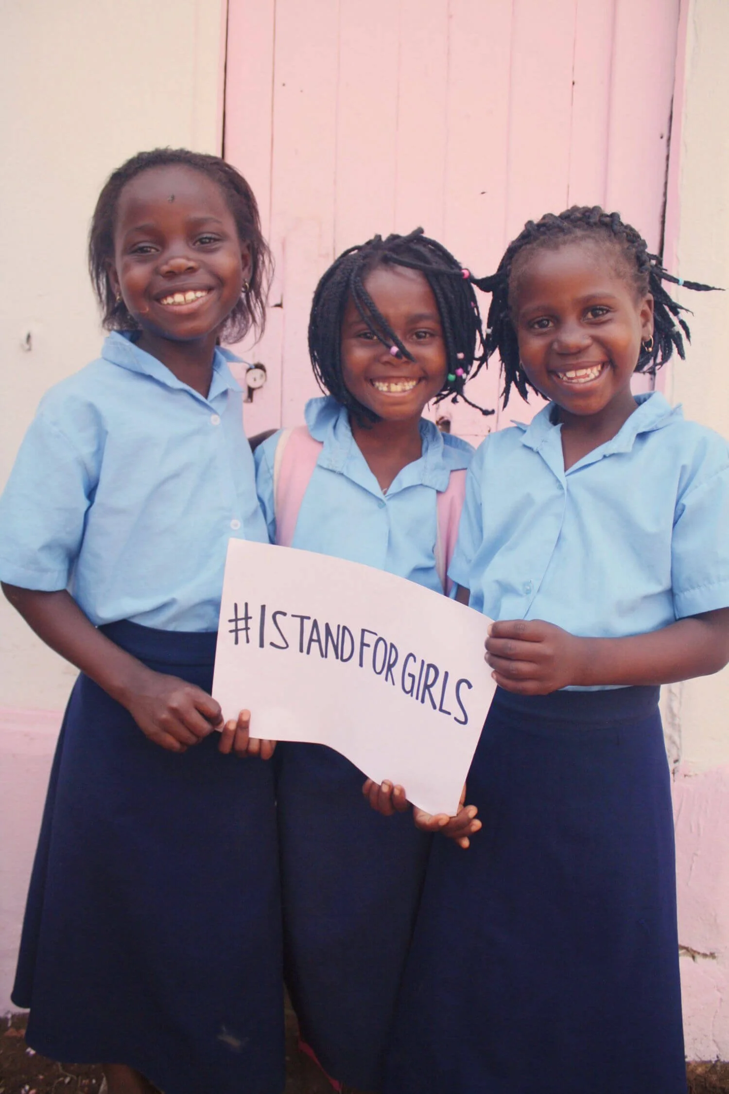 Young school girls in Mozambique holding #ISTANDFORGIRLS sign