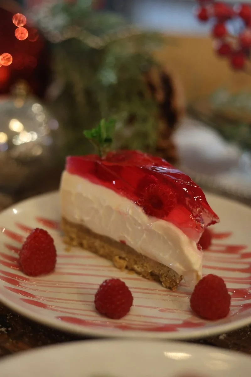 Slice of raspberry jelly cheesecake on a plate with fresh raspberries