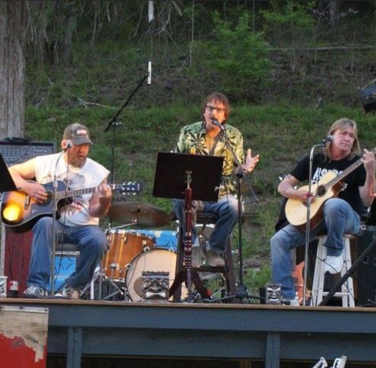 Kevin Michael Leis sings on stage and two guitarists