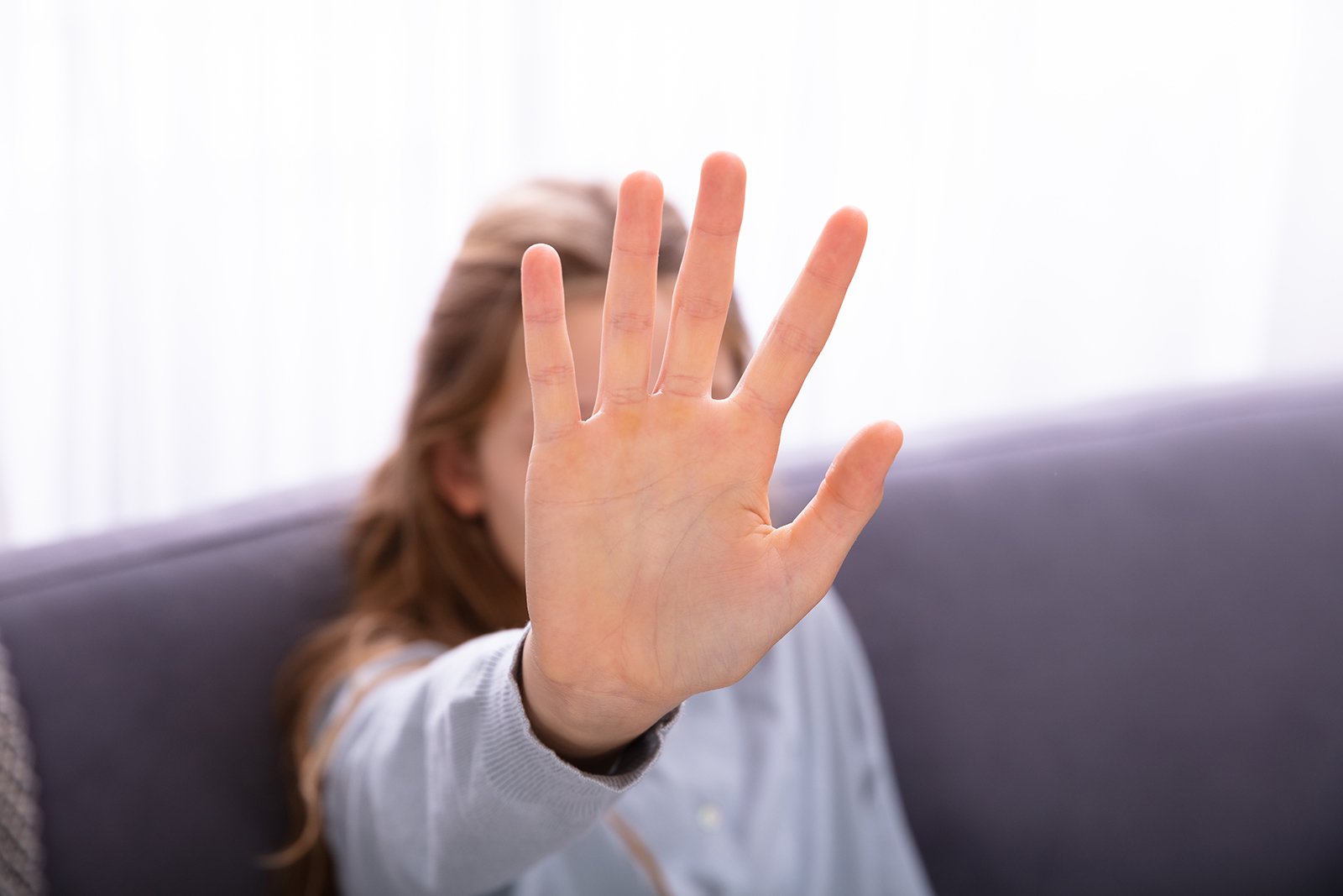 A photo of a girl holding up her hand hoping to avoid something