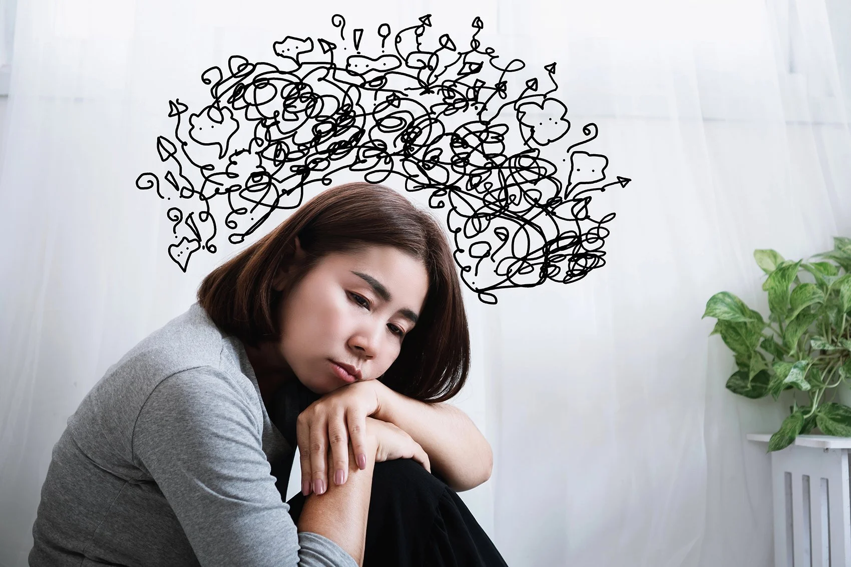 Picture of an asian woman who looks depresssed with scribbled "thoughts" above her head