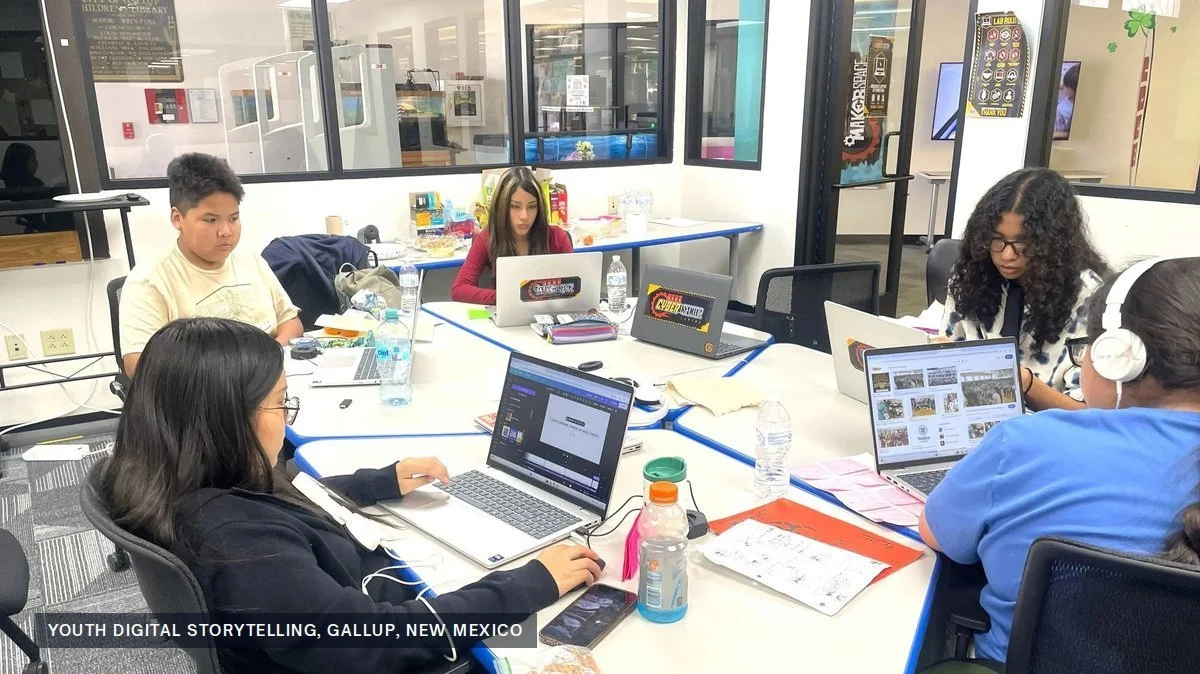 Five young people working on laptops around a table in a library makerspace in Gallup, New Mexico
