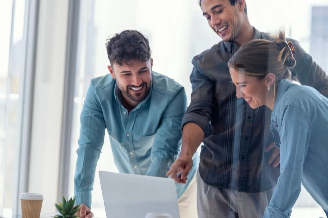Équipe de professionnels collaborant autour d’un ordinateur dans un environnement de travail.