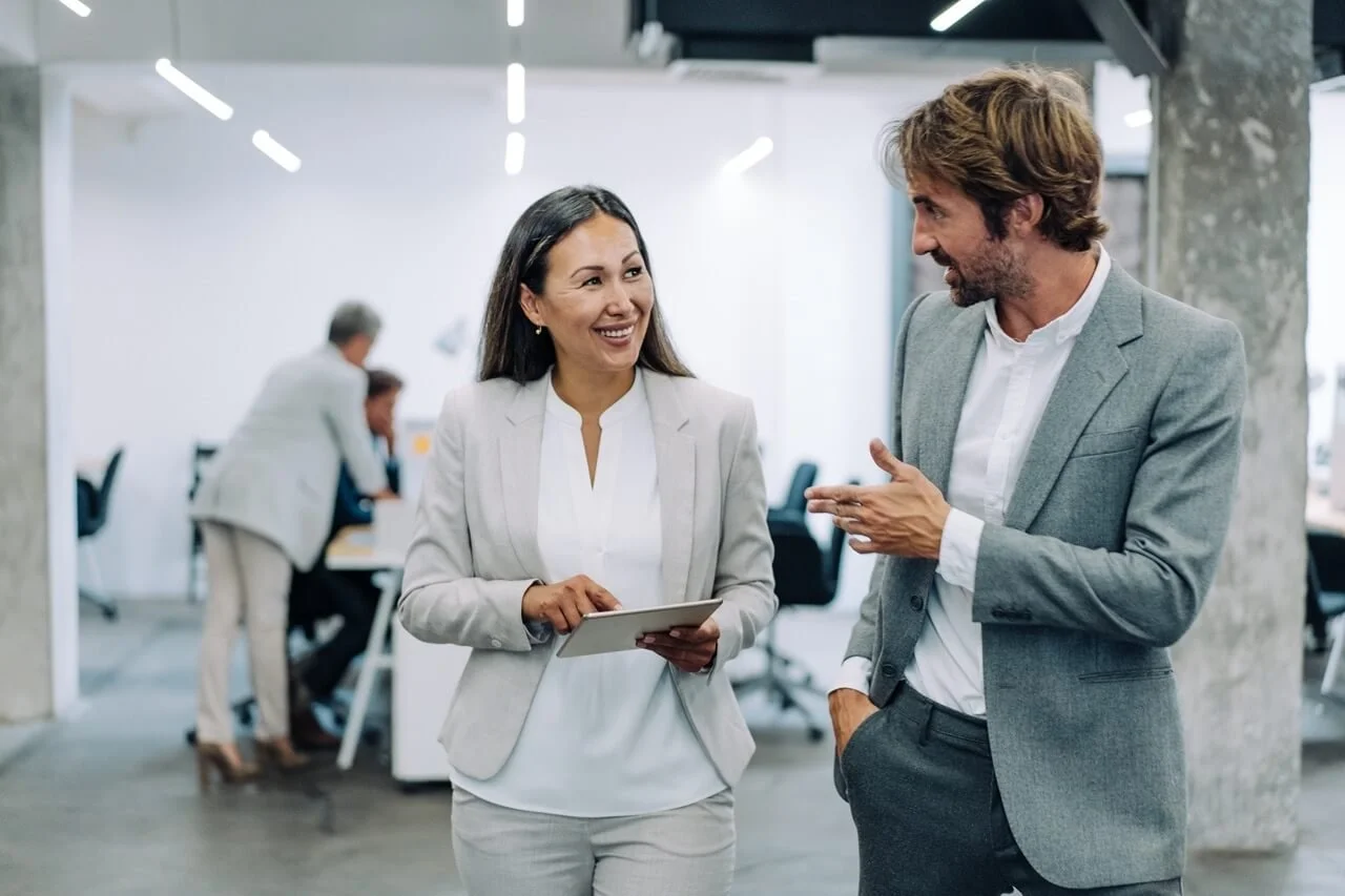 Deux professionnels échangent dans un environnement de travail, illustrant le coaching de gestion, la réflexion et le développement du leadership.