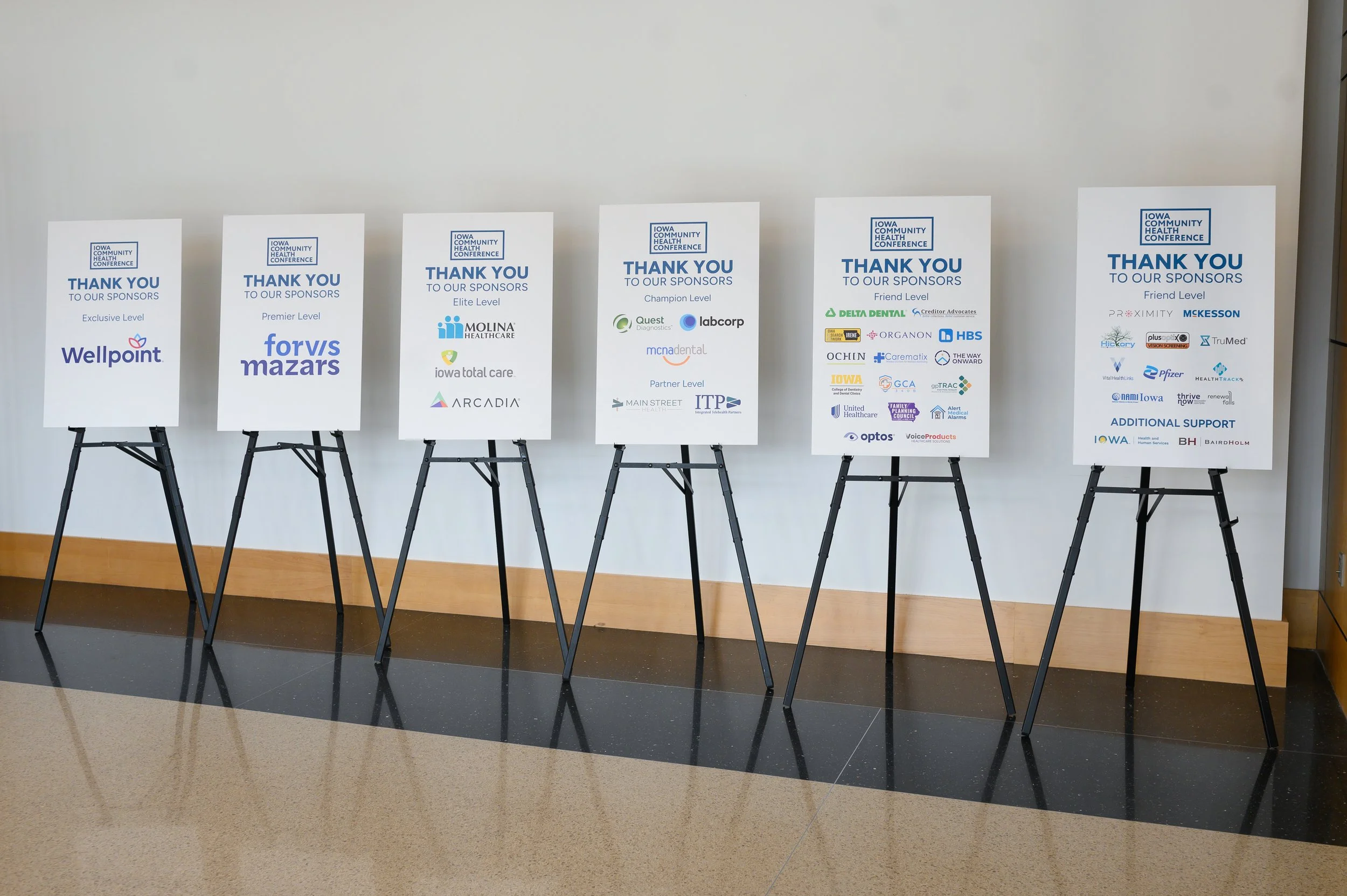 Row of poster boards display the event sponsors' logos