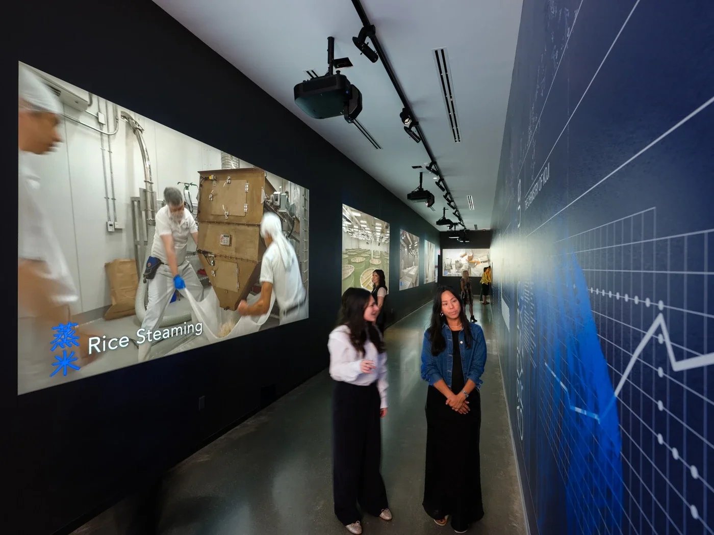 visitors-walk-through-an-exhibit-with-rice-processing-displays-on-the-wall.jpg.webp