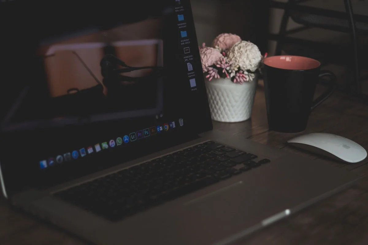 Squarespace SEO Services - shows a laptop on a desk next to a small vase of flowers and a black tea mug