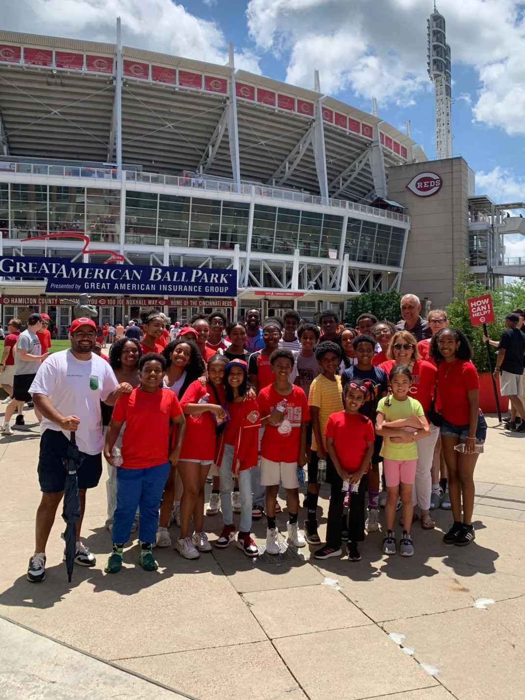 Group of children and adults in front of the entrance to Great American Ballpark, home of the Cincinnati Reds, in Cincinnati, Ohio, on a sunny day.