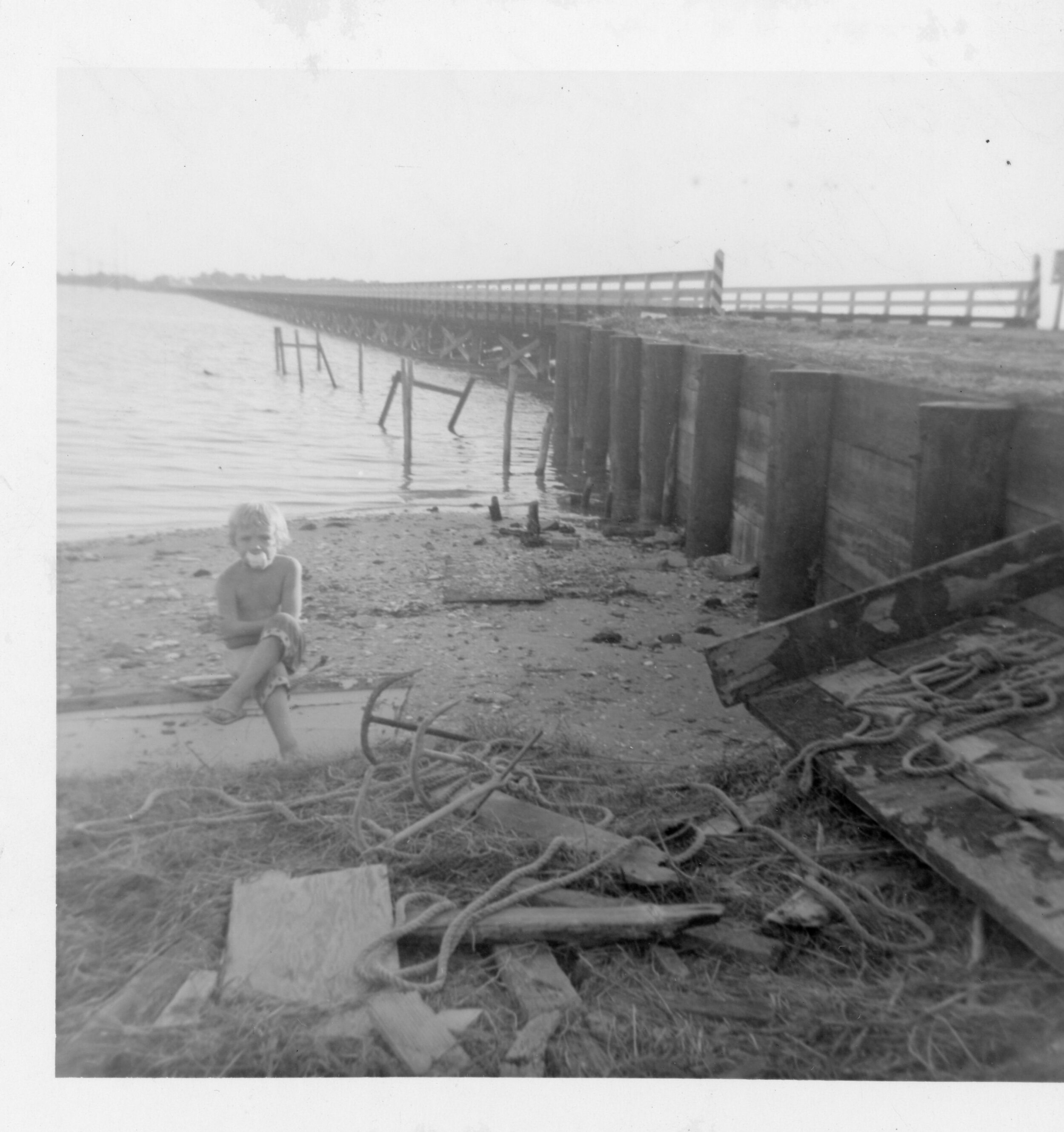 Ginger Chadwick sitting on a skiff beside where the Danny Damren’s boat dock used tobe–where he rented boats by the Harkers Island Bridge