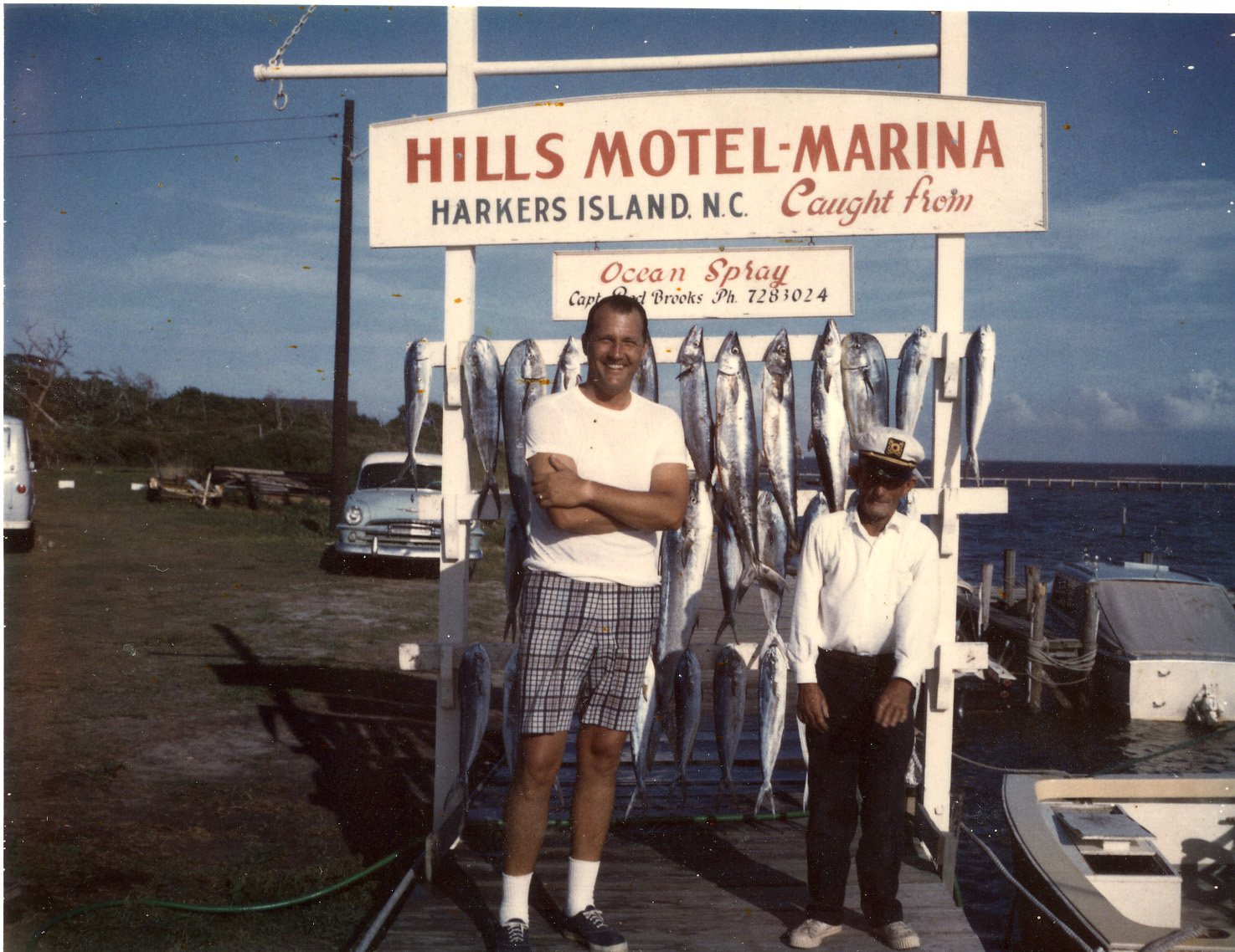 Charter boat captain Benny Rose with fishing party at his boat slip/ weigh station, Hills Motel, Harkers Island, 1960s.