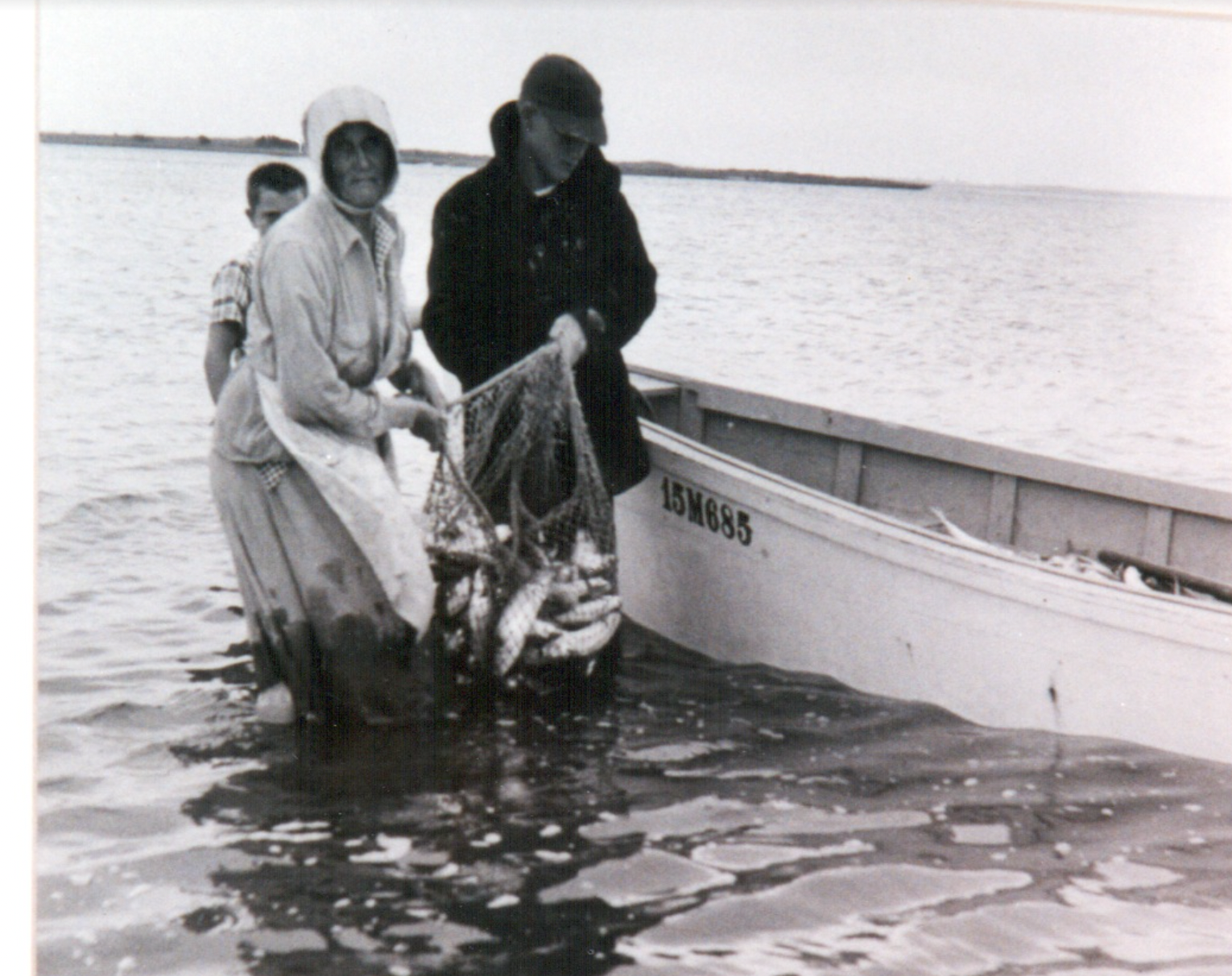 Ms. Dora, wearing her bonnet, in the water next to boat. Marvin is the barely visible boy standing behind her