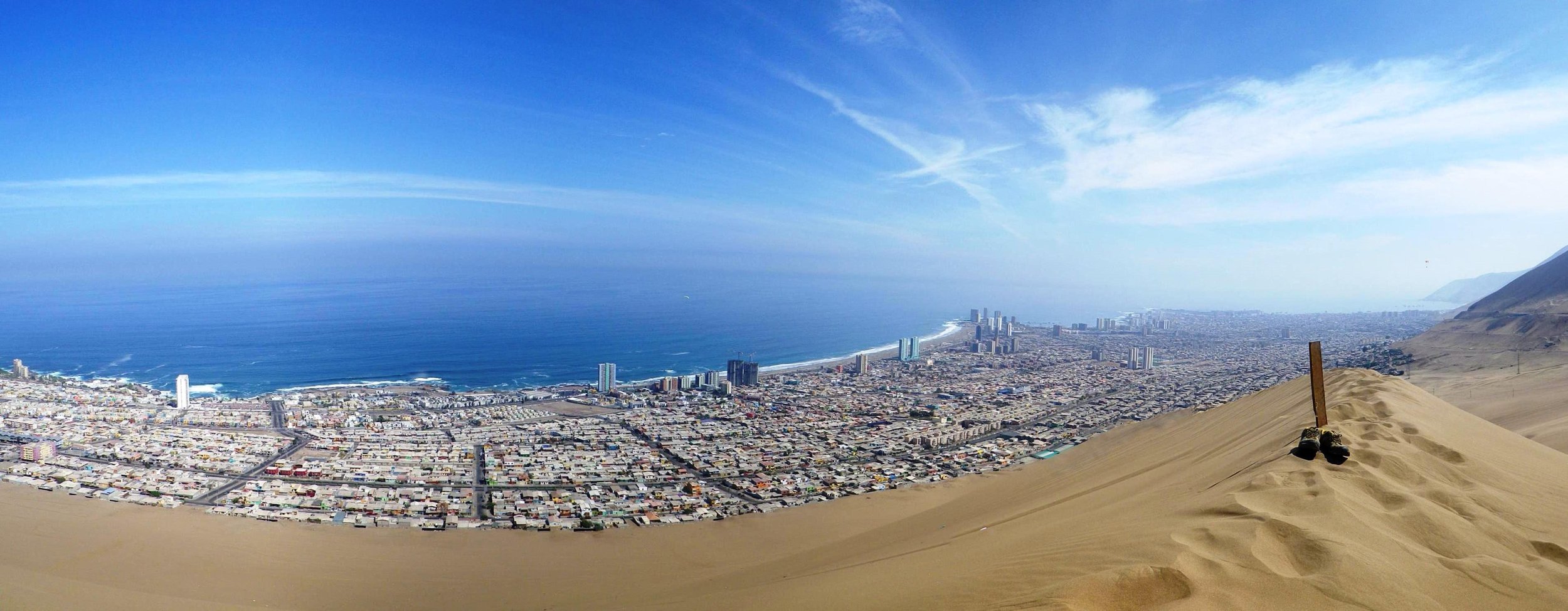 The coastal city of Iquique stretches along the seaside, backed by the Cerro Dragon dune at the edge of the city's development.