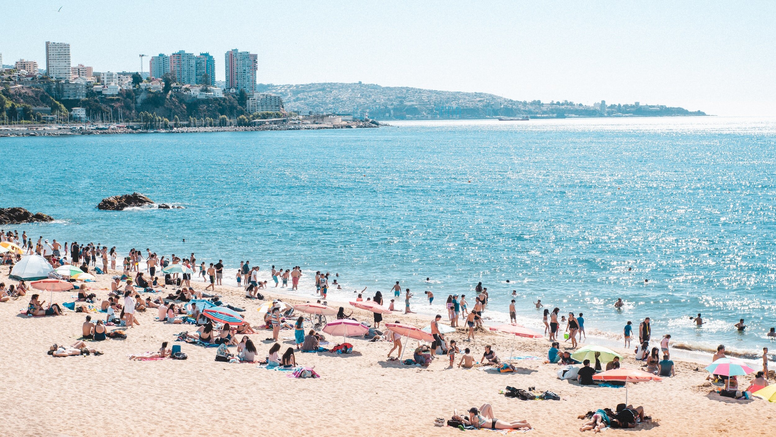 Swimmers and sun bathers enjoying a crowded beach, with high rise apartments off to the left, in Viña del Mar