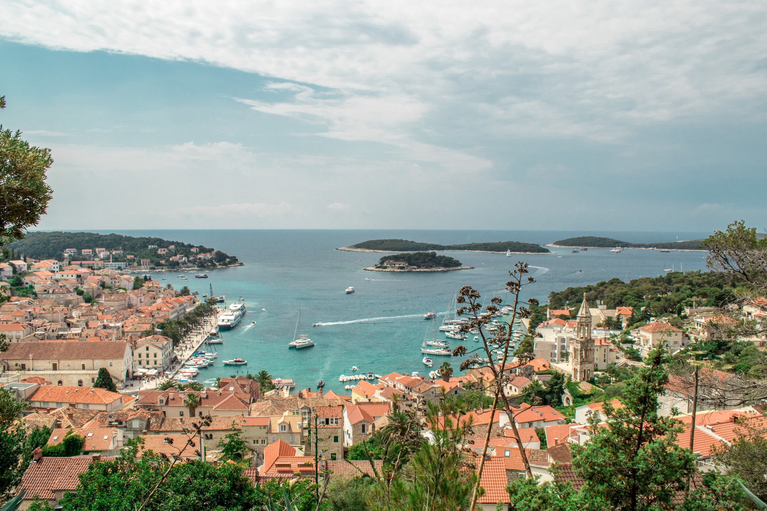 Hvar's charming old town and harbor, filled with boats and little islands, seen from a hill behind town.