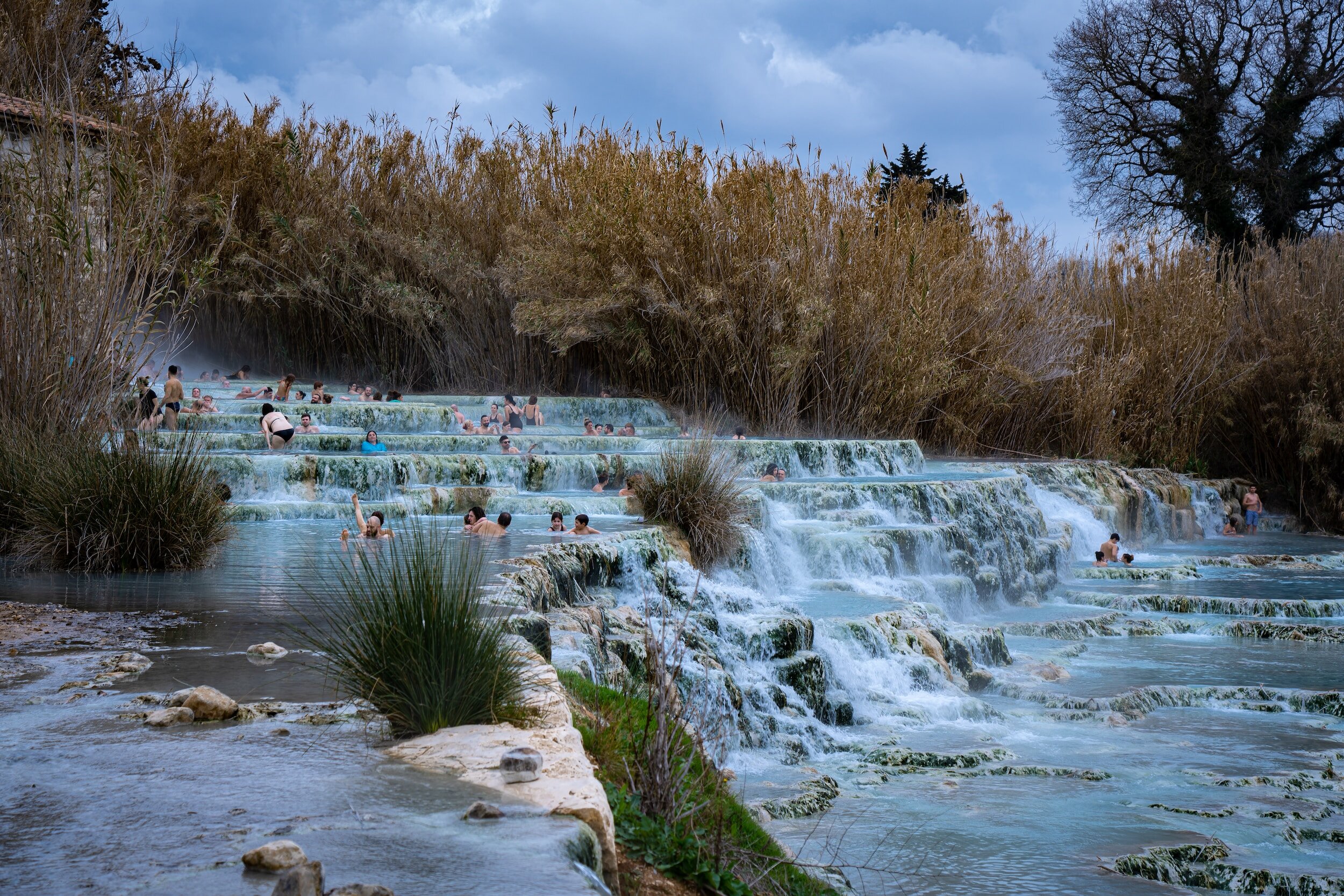 The cascading falls and hot spring pools filled with people in the Terme di Saturnia