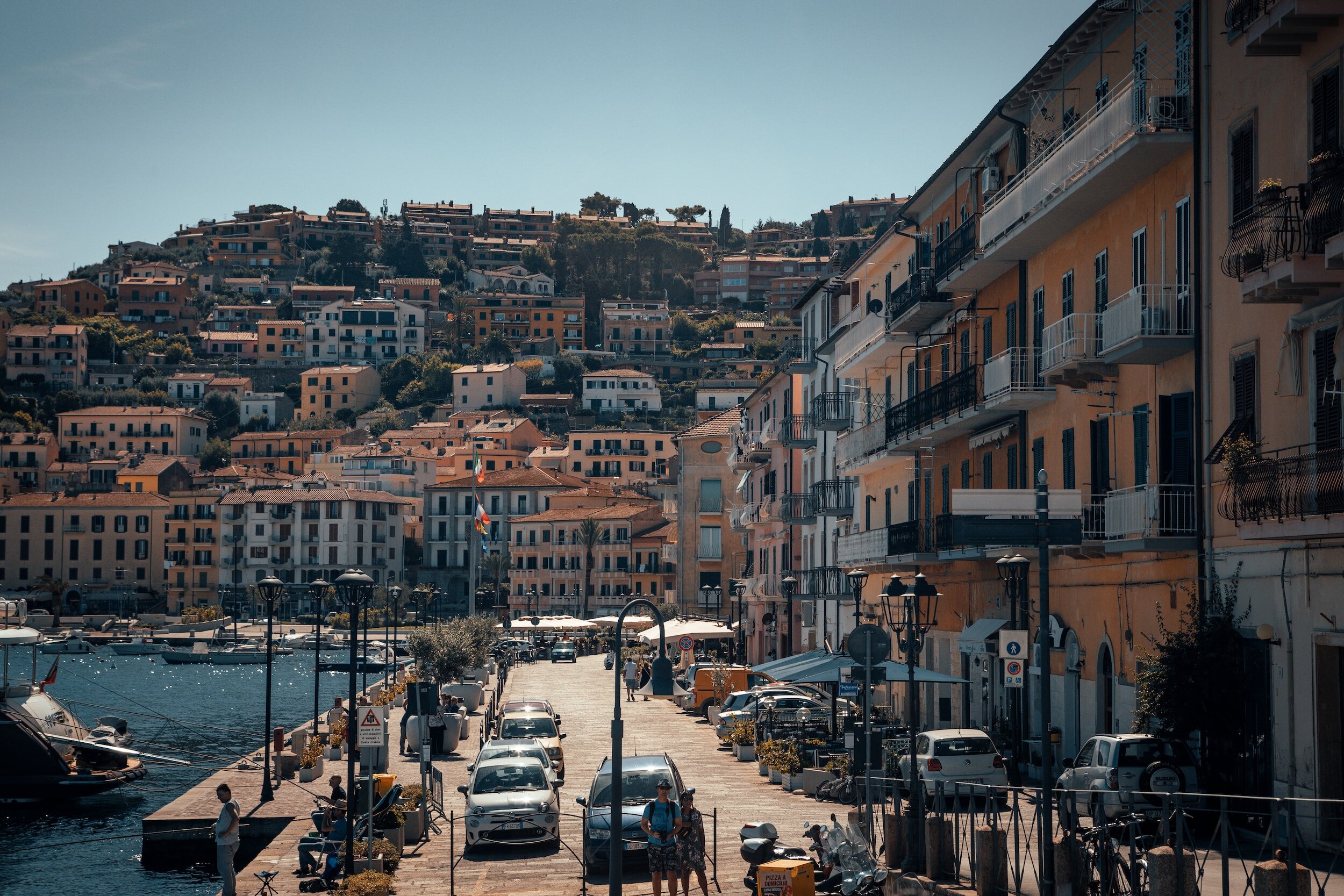 The waterfront of the town of Porto Santo Stefano, with buildings running along the main street on the right, and the sea on the left