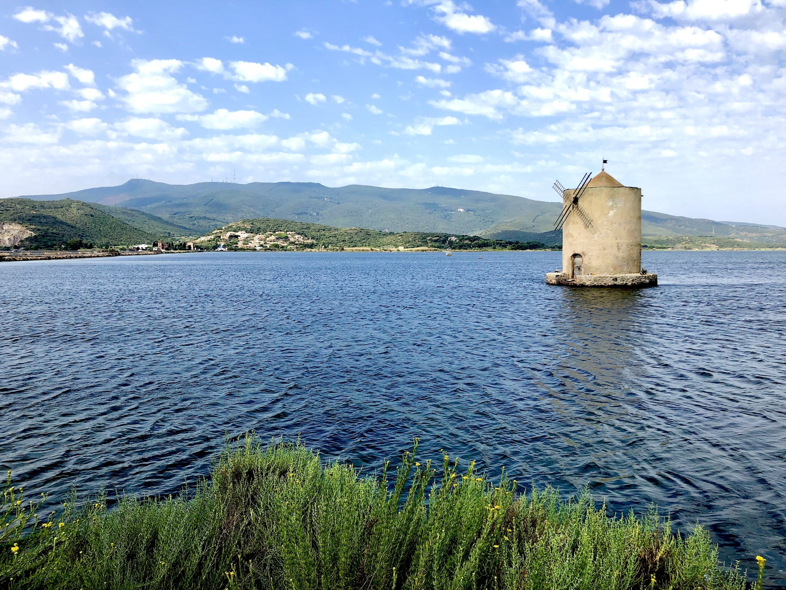 A stone windmill sitting in the middle of the Laguna di Orbetello in the town of Orbetello