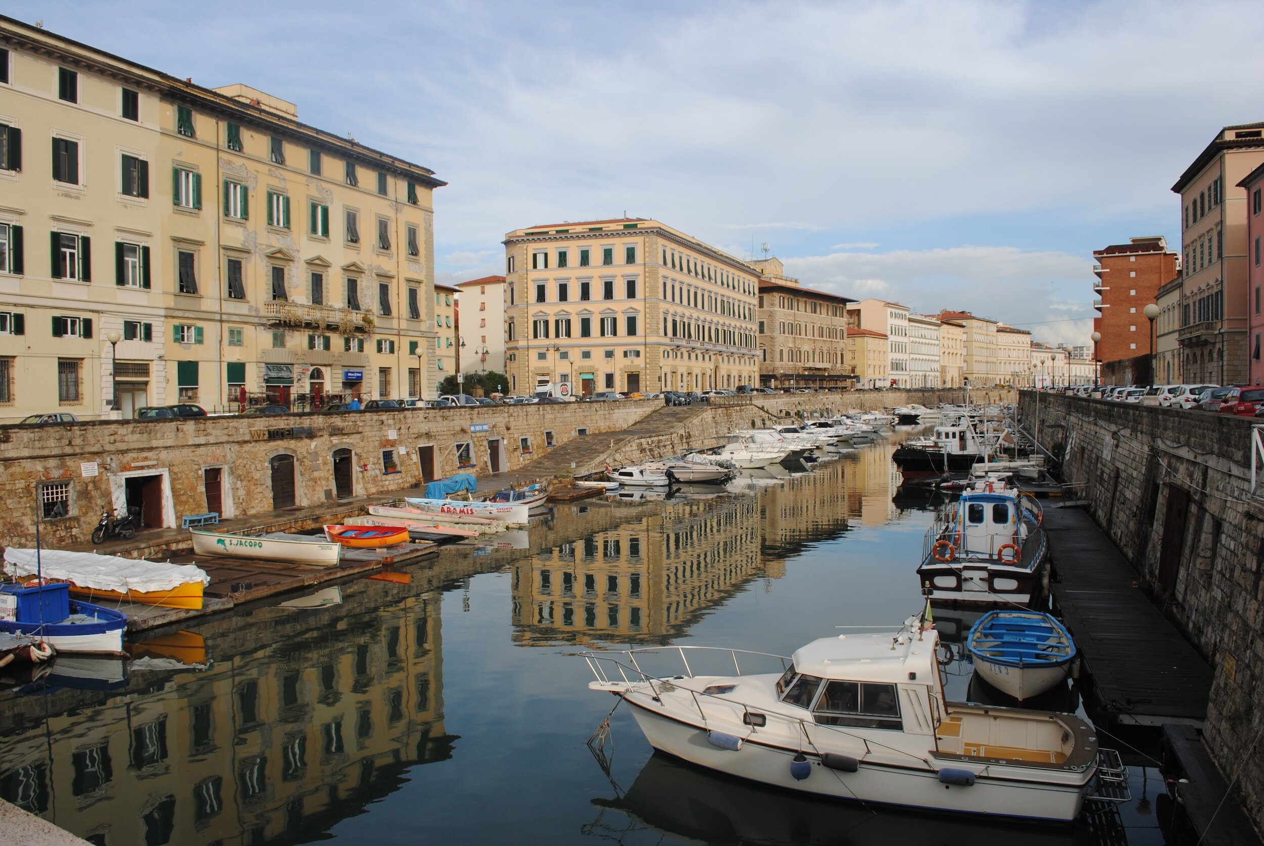 A canal in Livorno, with boats docked in the water and buildings stretching along either side of the waterfront