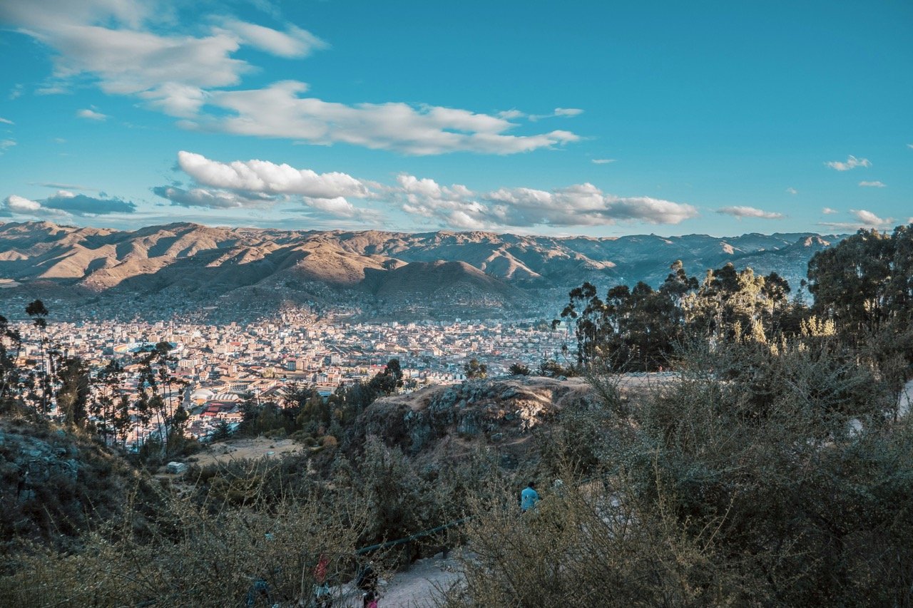 The city of Cusco and the mighty Andes mountains surrounding it seen through scrub high above the city at the Q'enko archaeological site.