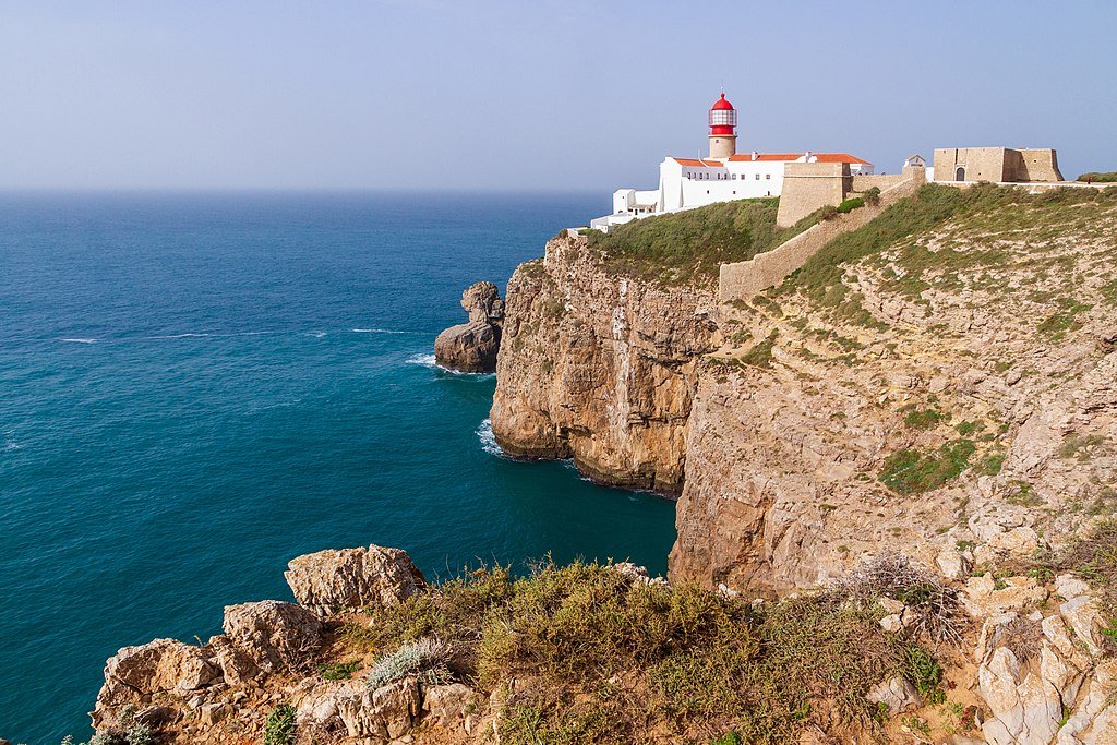 The lighthouse of Cabo de Sao Vicente seen from the surrounding cliffs, which drop straight into the blue ocean below