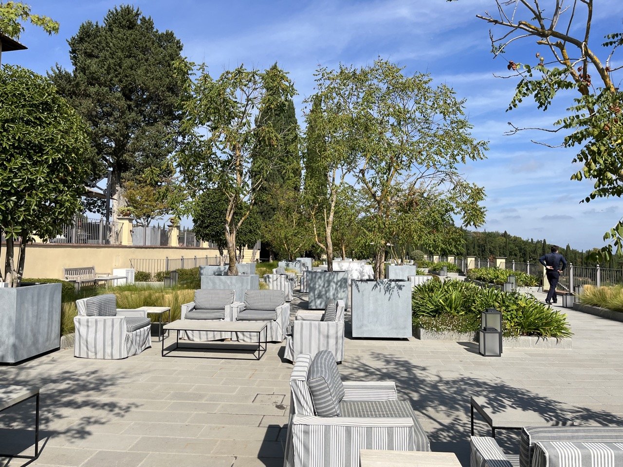 The outdoor seating area featuring loungers, sofas, and bright green trees and plants at the Castello del Nero luxury hotel in the town of Barberino, in Italy's Chianti region.