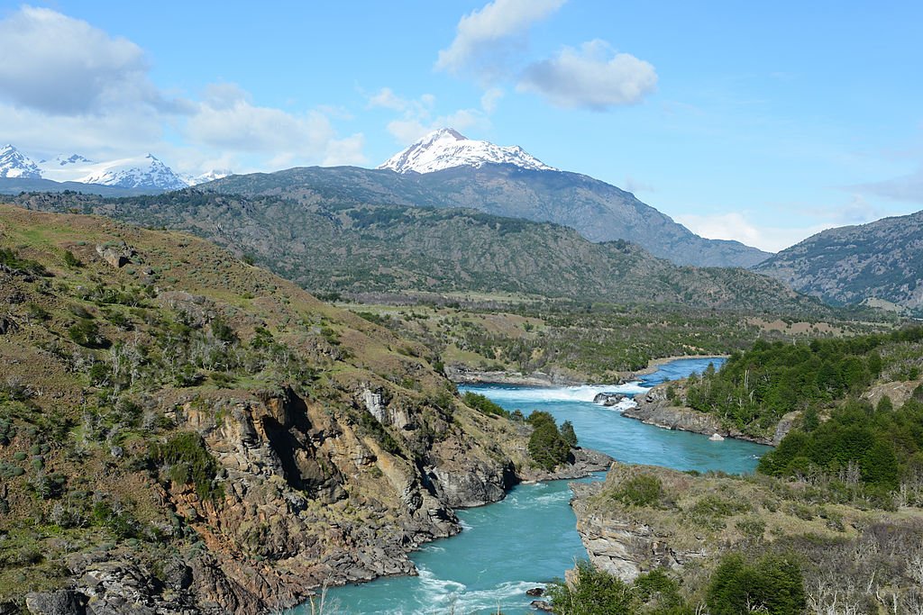 Hills give way to rugged granite peaks in a valley crossed by a glacial stream along Chile's Carretera Austral.