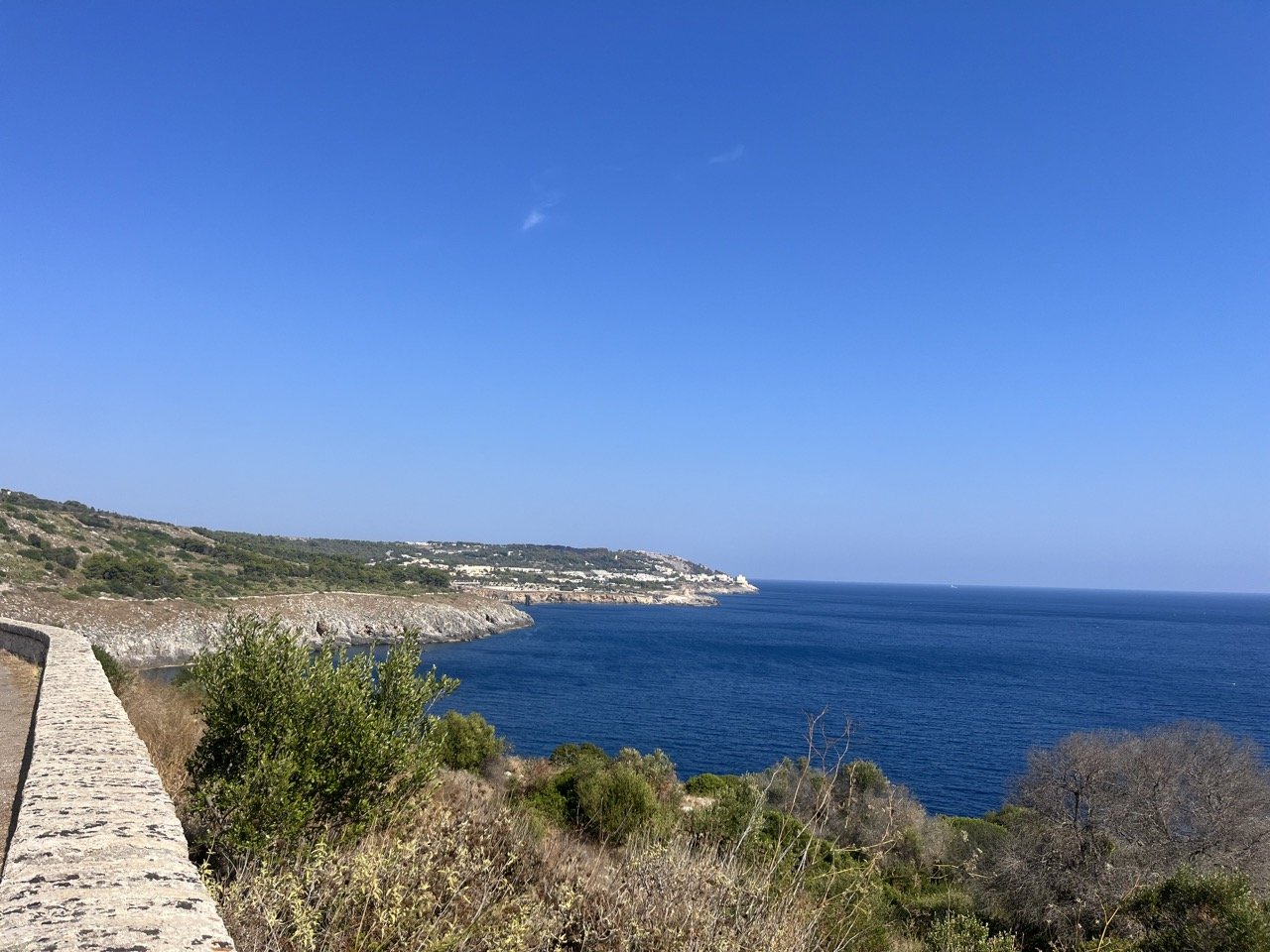 A stretch of rocky coastline with a deep blue sea on a sunny fall day in southern Salento, Puglia.