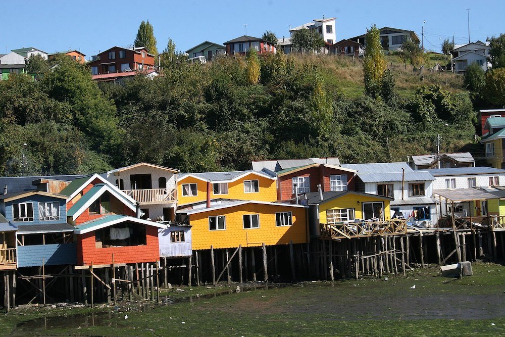Colorful Palafito houses sit atop stilts above the water in Chiloe, Chile.