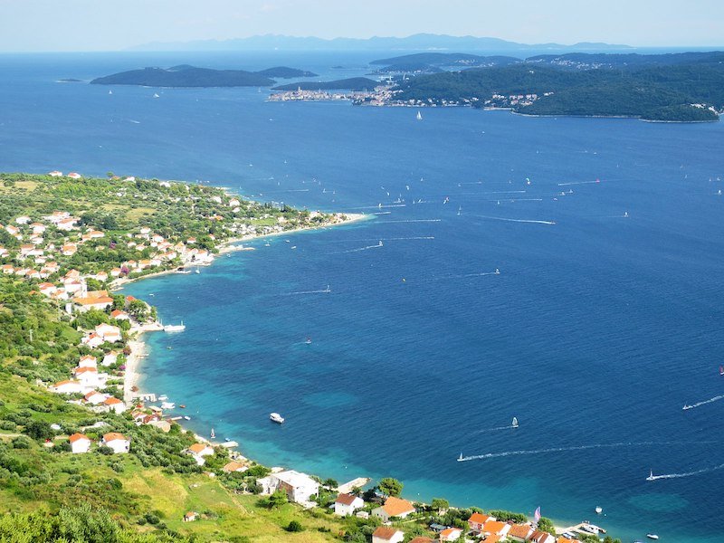 Dozens of sailboats plying the waters along the coast of the town of Viganj in the Pelješac peninsula as seen from high above.