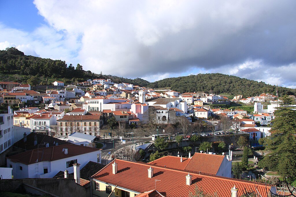 The town of Monchique and its picturesque white and red buildings, nestled amongst green, forested hills.