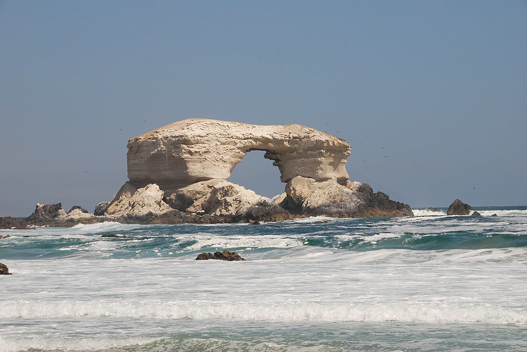 The stone arch of La Portada National Monument rises out of the water and waves on the coast near to Antofagasta.