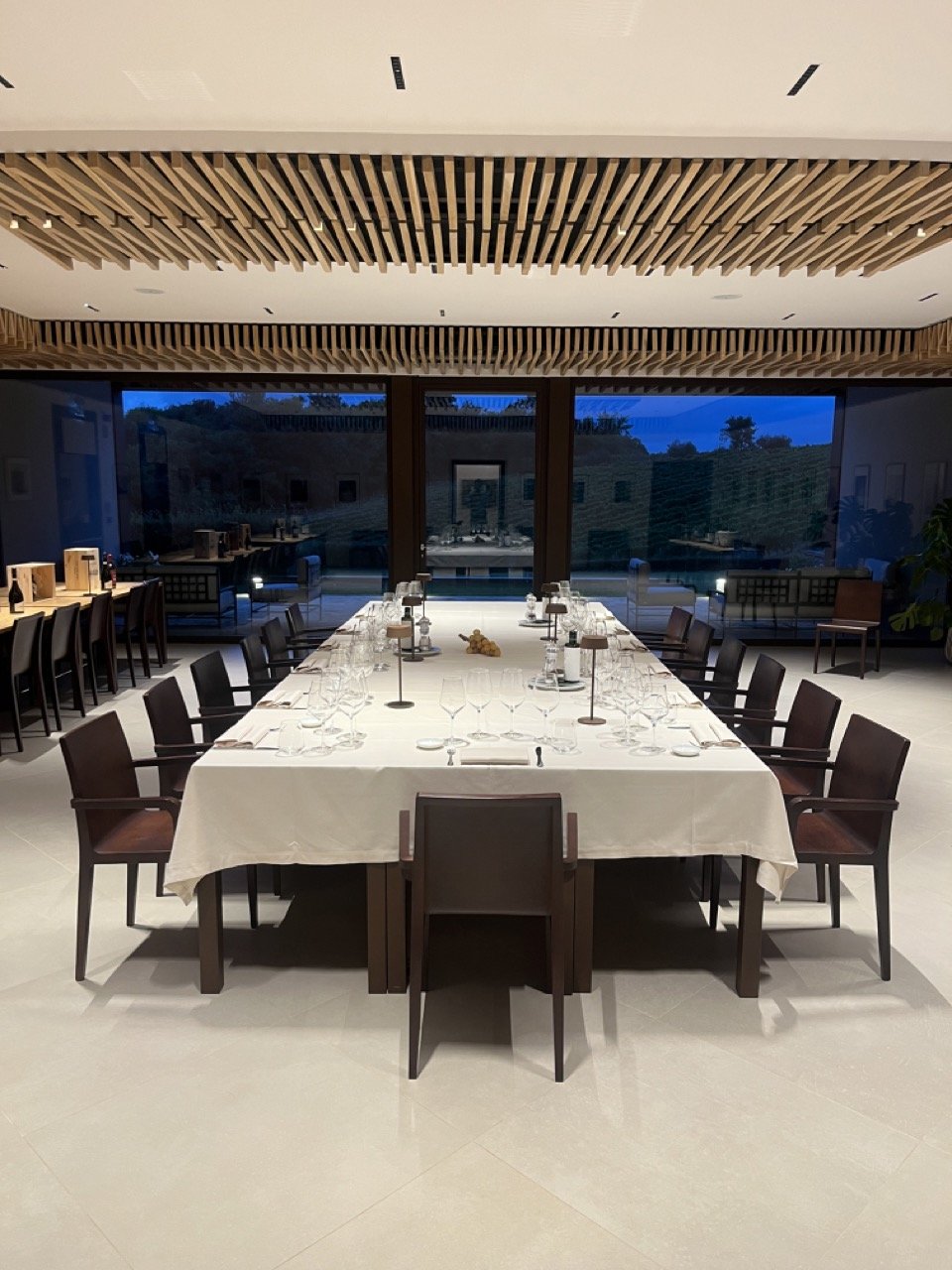 The wine tasting room with a large table, elegantly set with wine glasses and silverware in preparation for a wine tasting at the Vallepicciola winery in Tuscany's Chianti region.