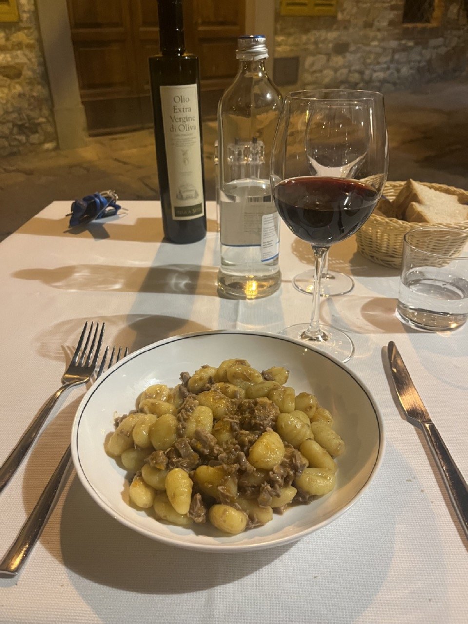 A plate of pasta with a glass of red wine in front of it at a restaurant near to Castelnuovo Berardenga in Tuscany's Chianti wine region.