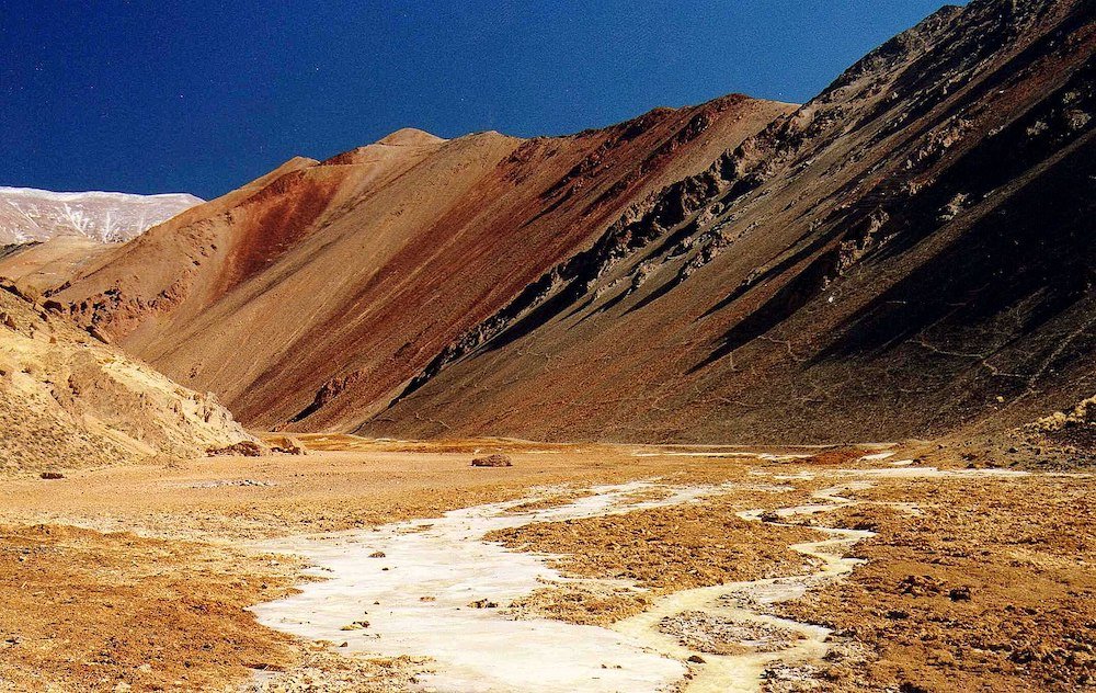 The red earth valley of Suriplaza, surrounded by mountains streaked all different colors near to Putre, Chile.
