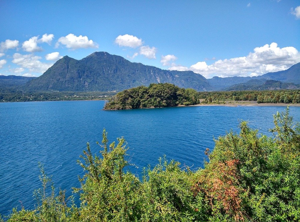 The calm waters of Calafuén Lake surrounded by mountains and forests.