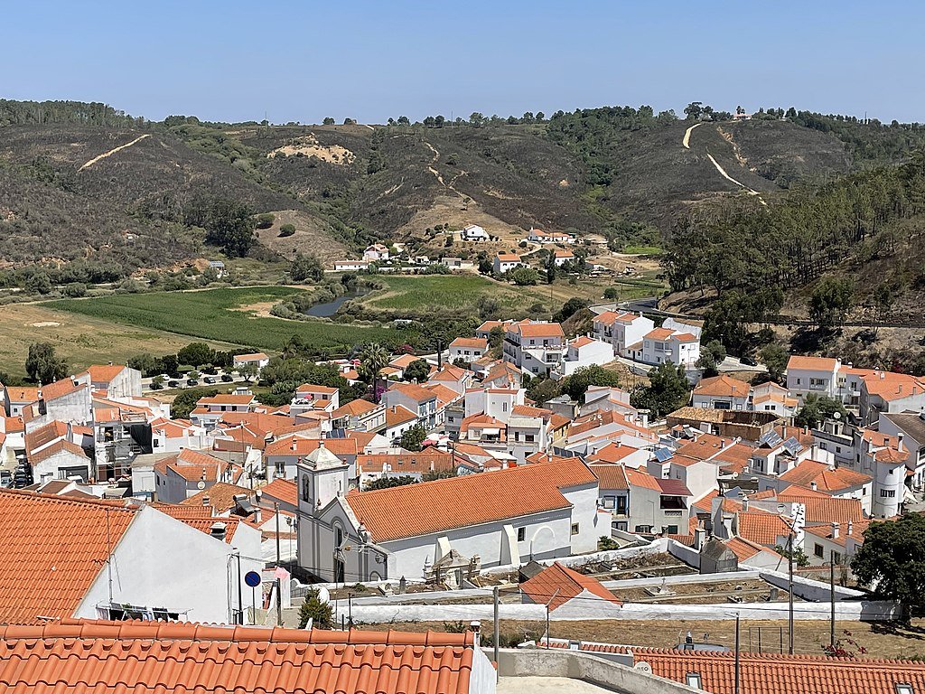 A jumble of white plaster and red tile roof buildings seen from a hill outside of town in Odeceixe, Portugal.