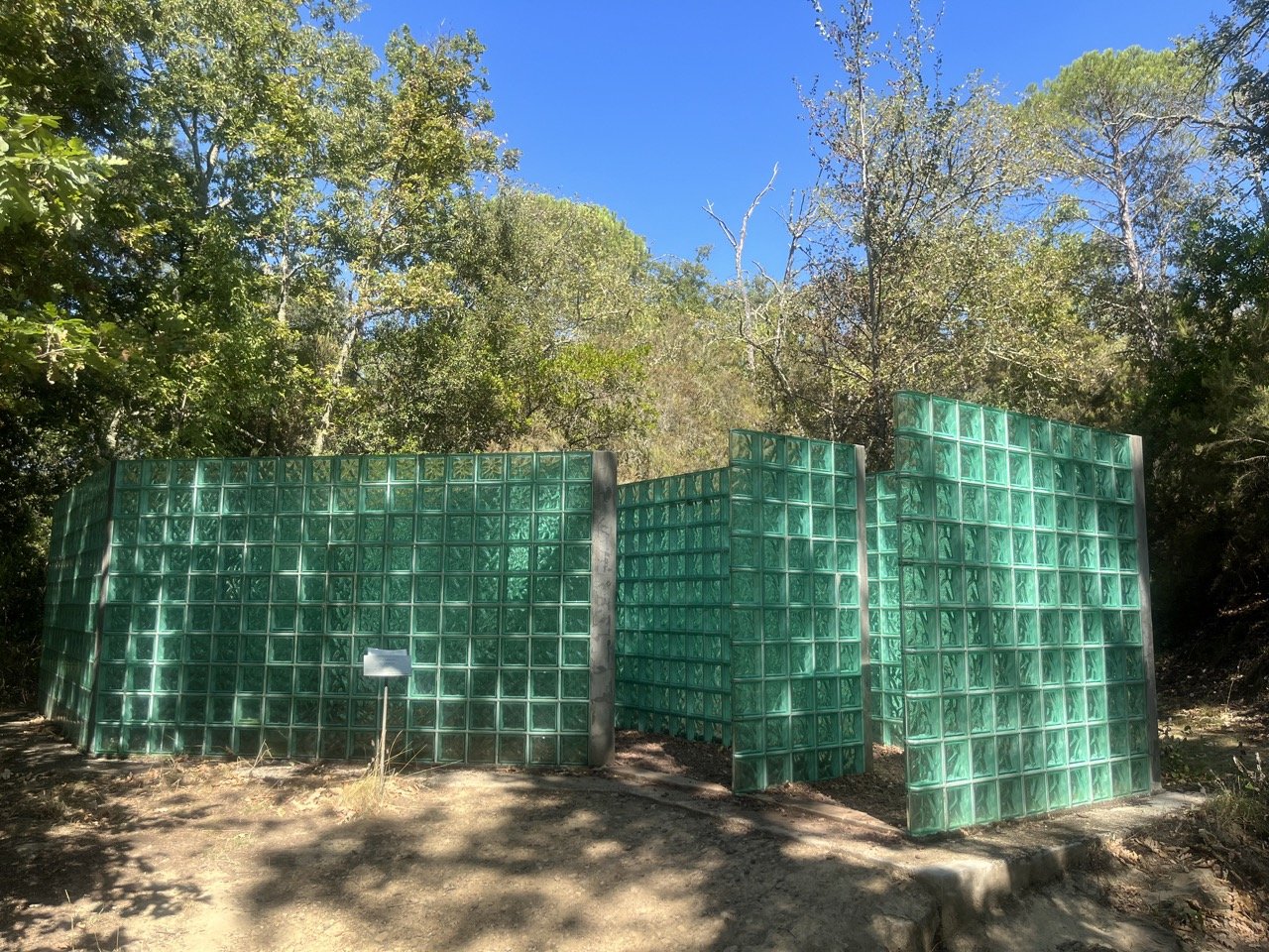 A green-blue glass block maze in the midst of the forest in the Chianti sculpture park.