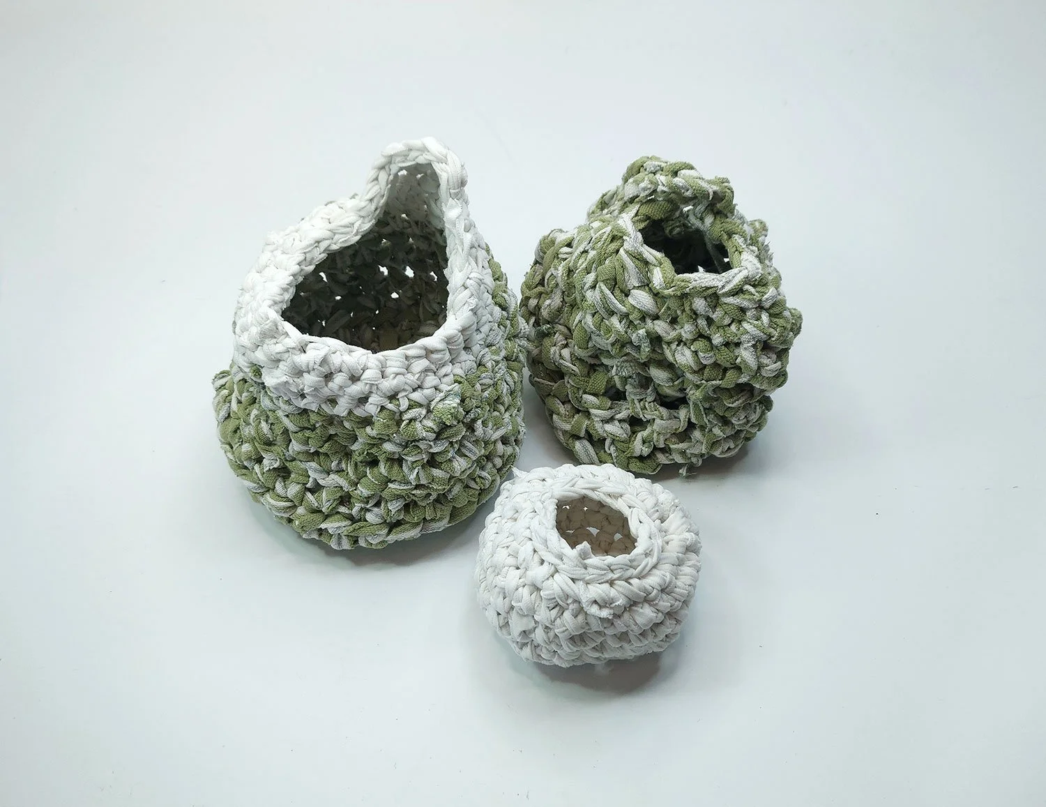 Three handmade textile containers crocheted with recycled fabric..