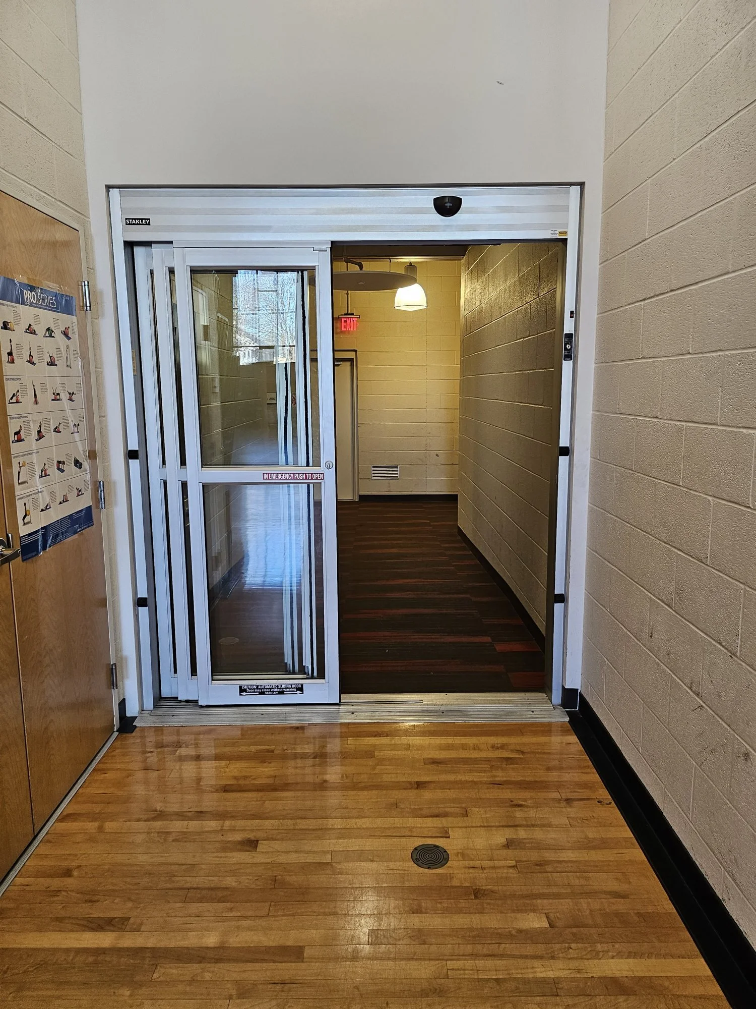 Automatic sliding door with breakaway panels in a commercial hallway