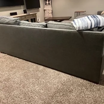 Gray upholstered sofa with striped accent pillow — Brothers Furniture restoration for a simple, modern living room.