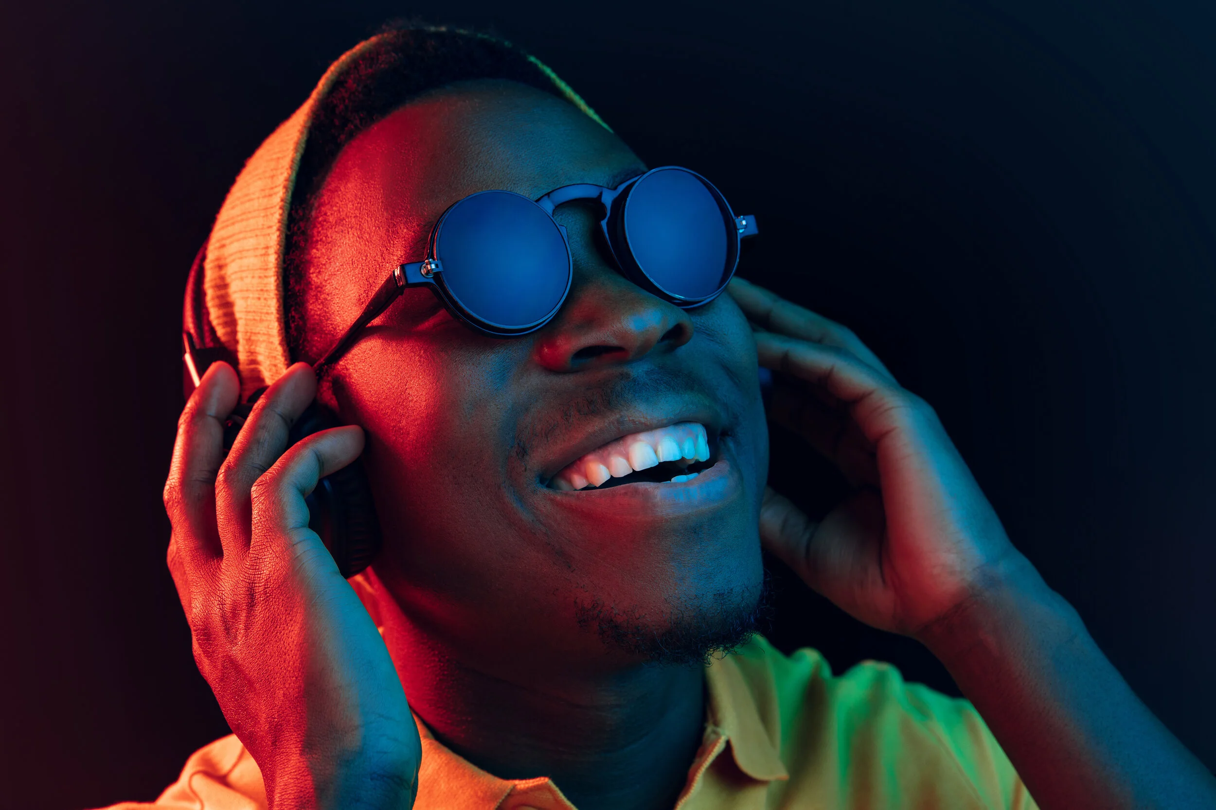 young-hipster-man-listening-music-with-headphones-black-studio-with-neon-lights.jpg