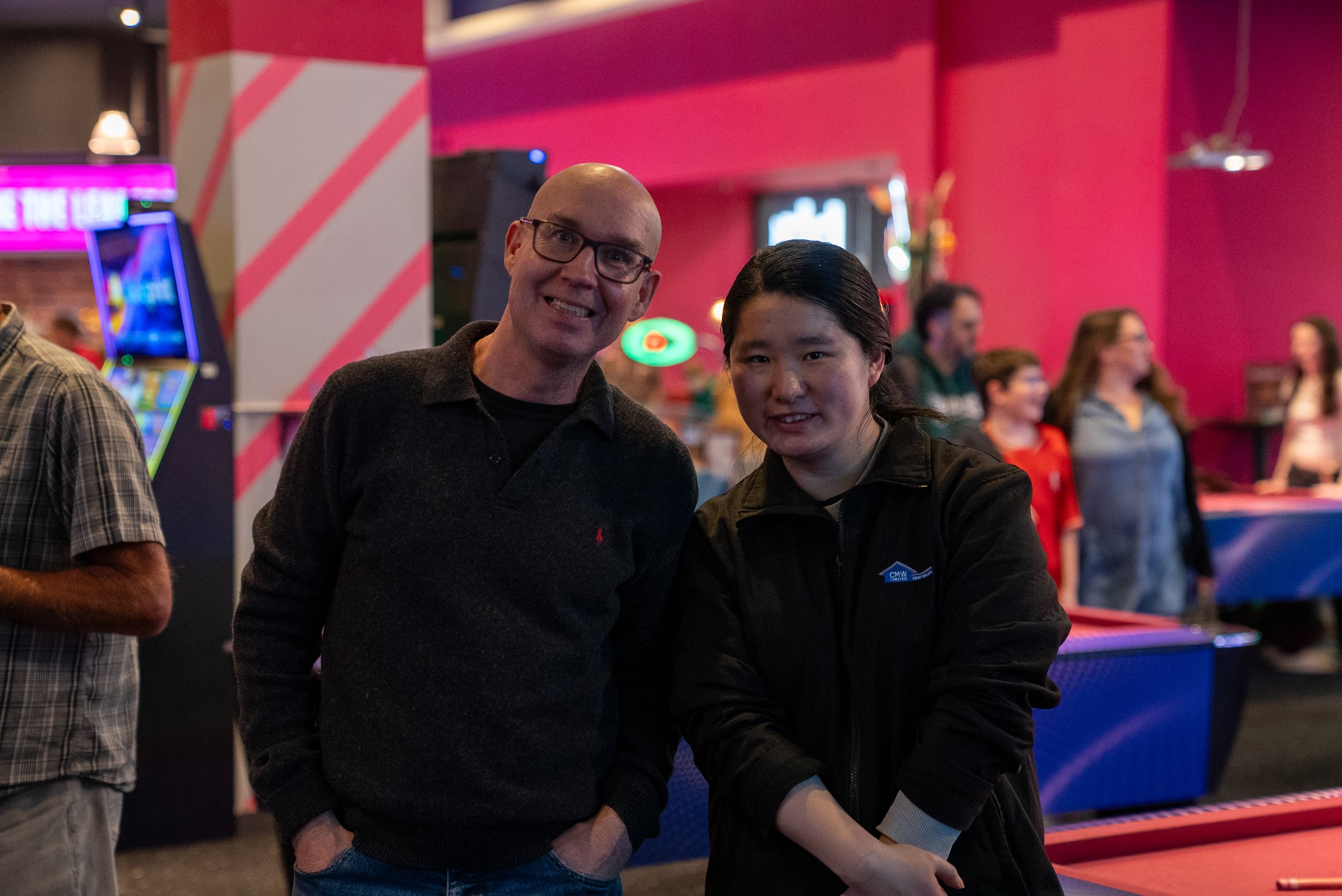 Two people smiling in a colorful indoor entertainment venue.