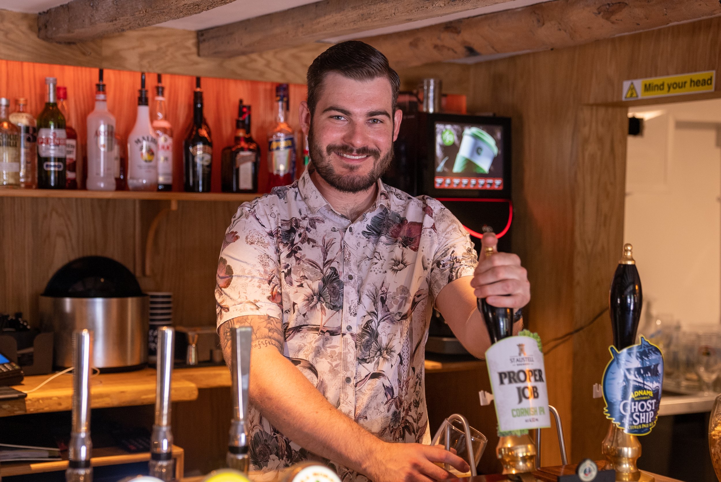 Bartender pouring drinks in a wooden bar, bottles in background