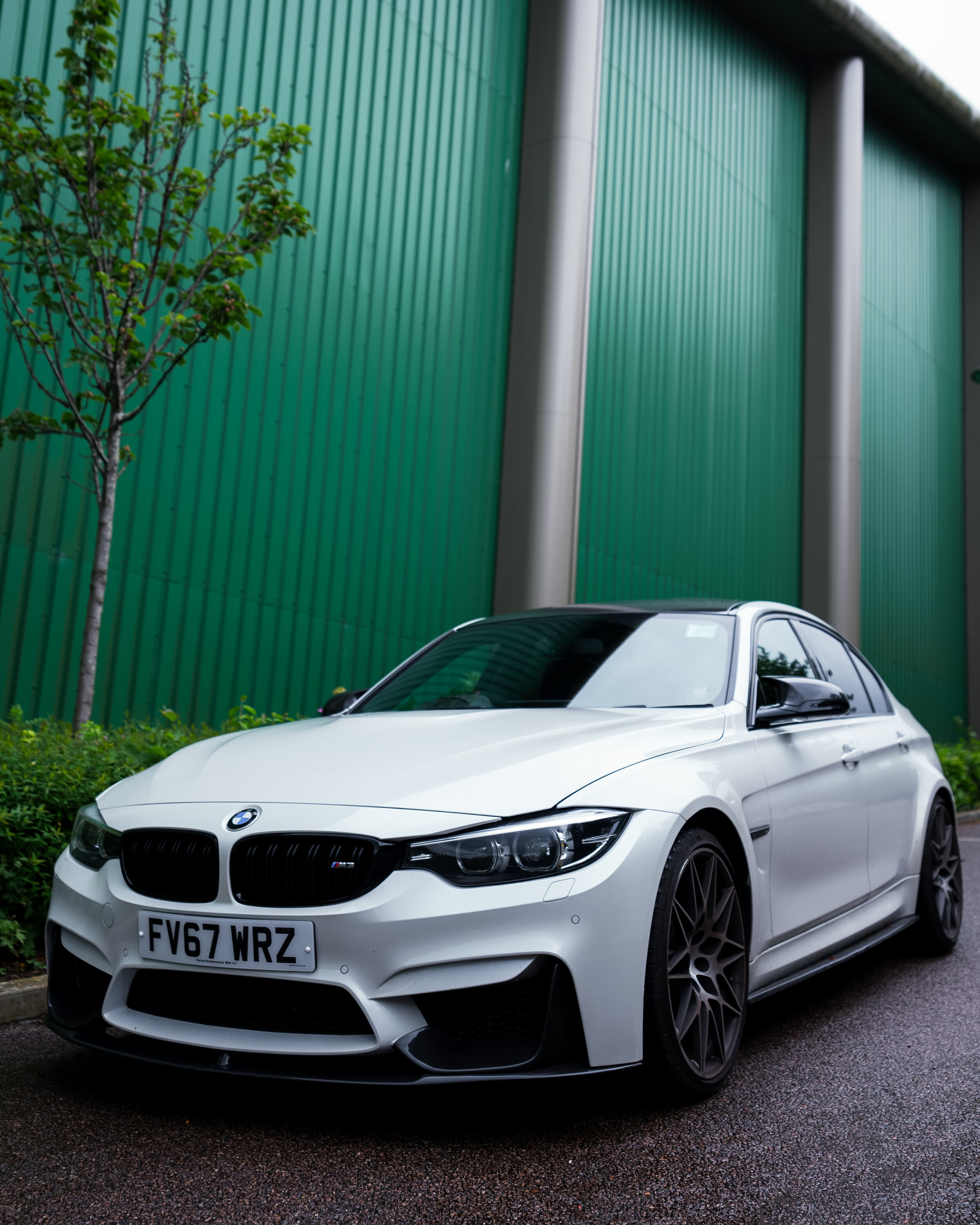 White BMW parked in front of a green industrial building