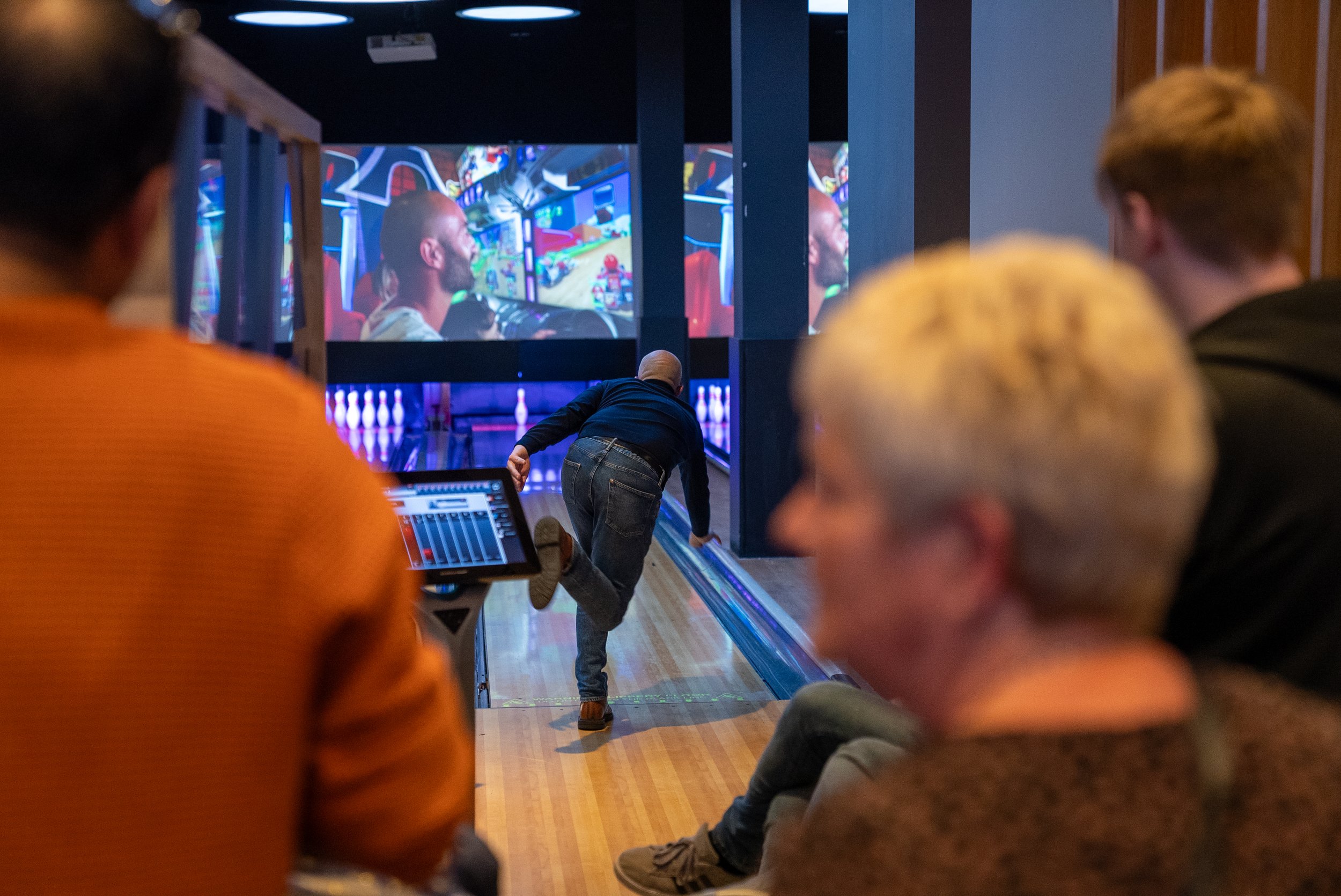 Person bowling in indoor alley with digital screens