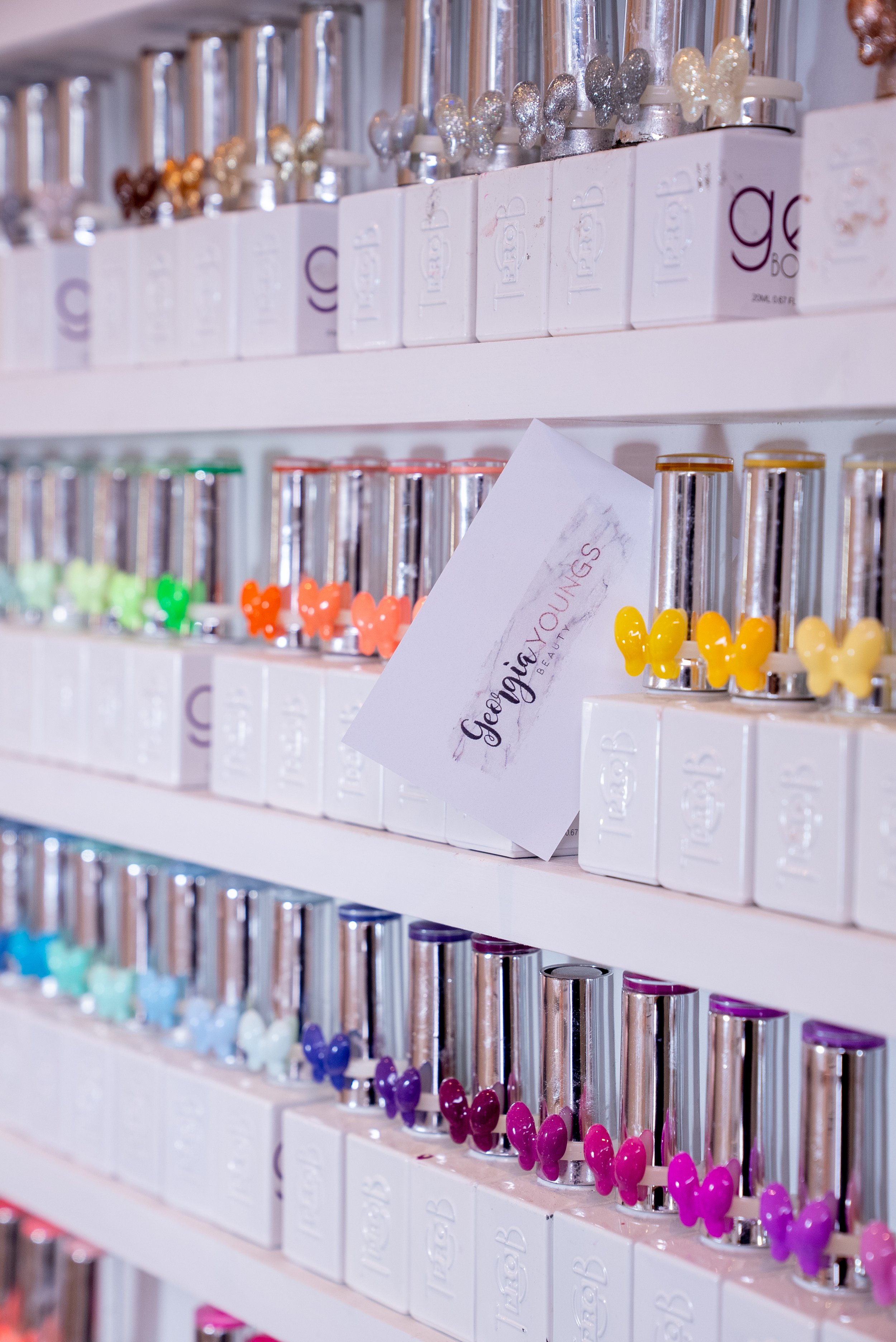 Colorful gel nail polish bottles on a shelf with butterfly-shaped swatches.