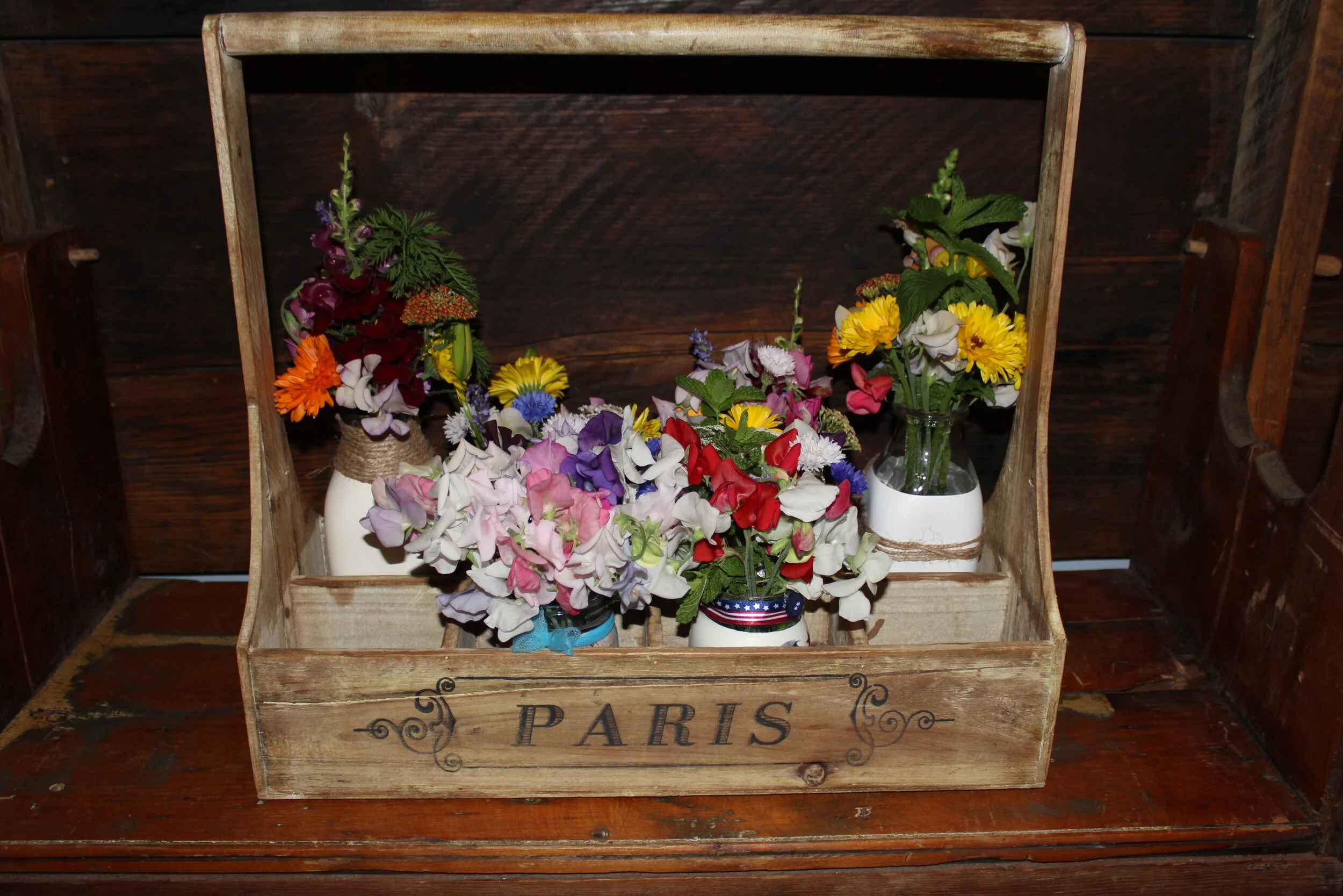 Wooden box labeled 'Paris' with colorful flowers in jars